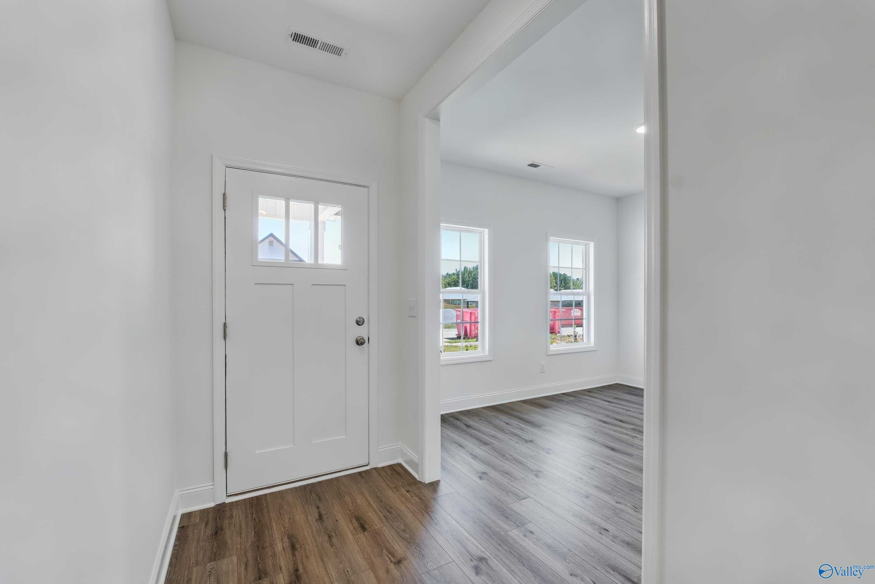 Bright entryway with white paneled door, large windows, and hardwood floors in Davidson Homes The Shelby A, Arab, Alabama