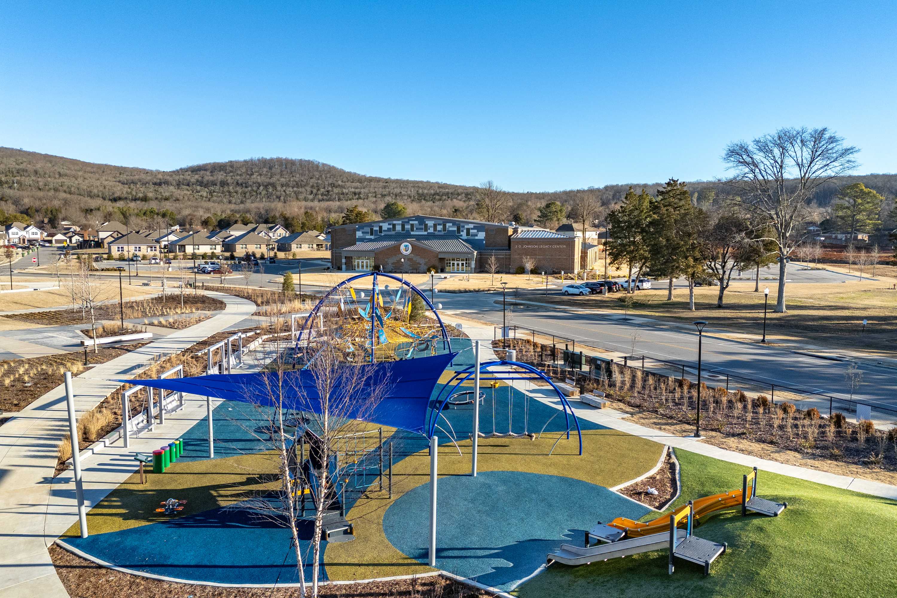 Vibrant community playground at Jaguar Hills in Huntsville Alabama with blue shaded canopy colorful slides climbing structures and surrounding homes