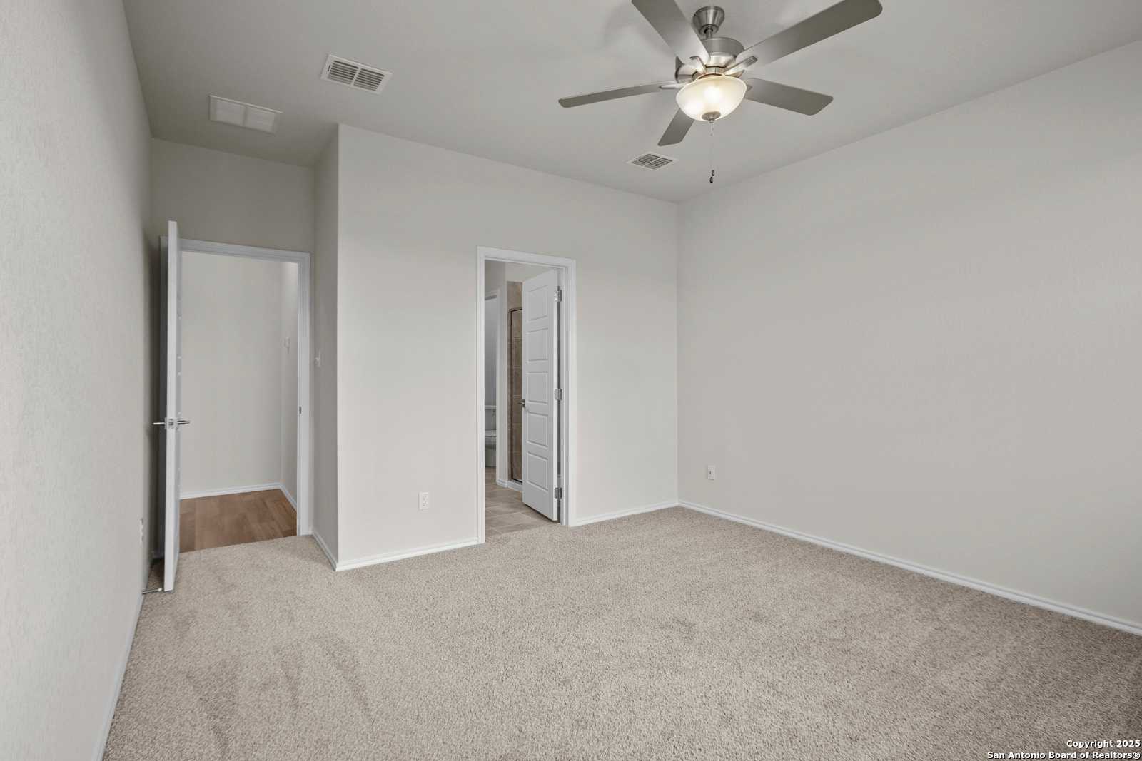 Spacious master bedroom with ceiling fan, en-suite bath, and walk-in closet in Davidson Homes The Asheville J, San Antonio
