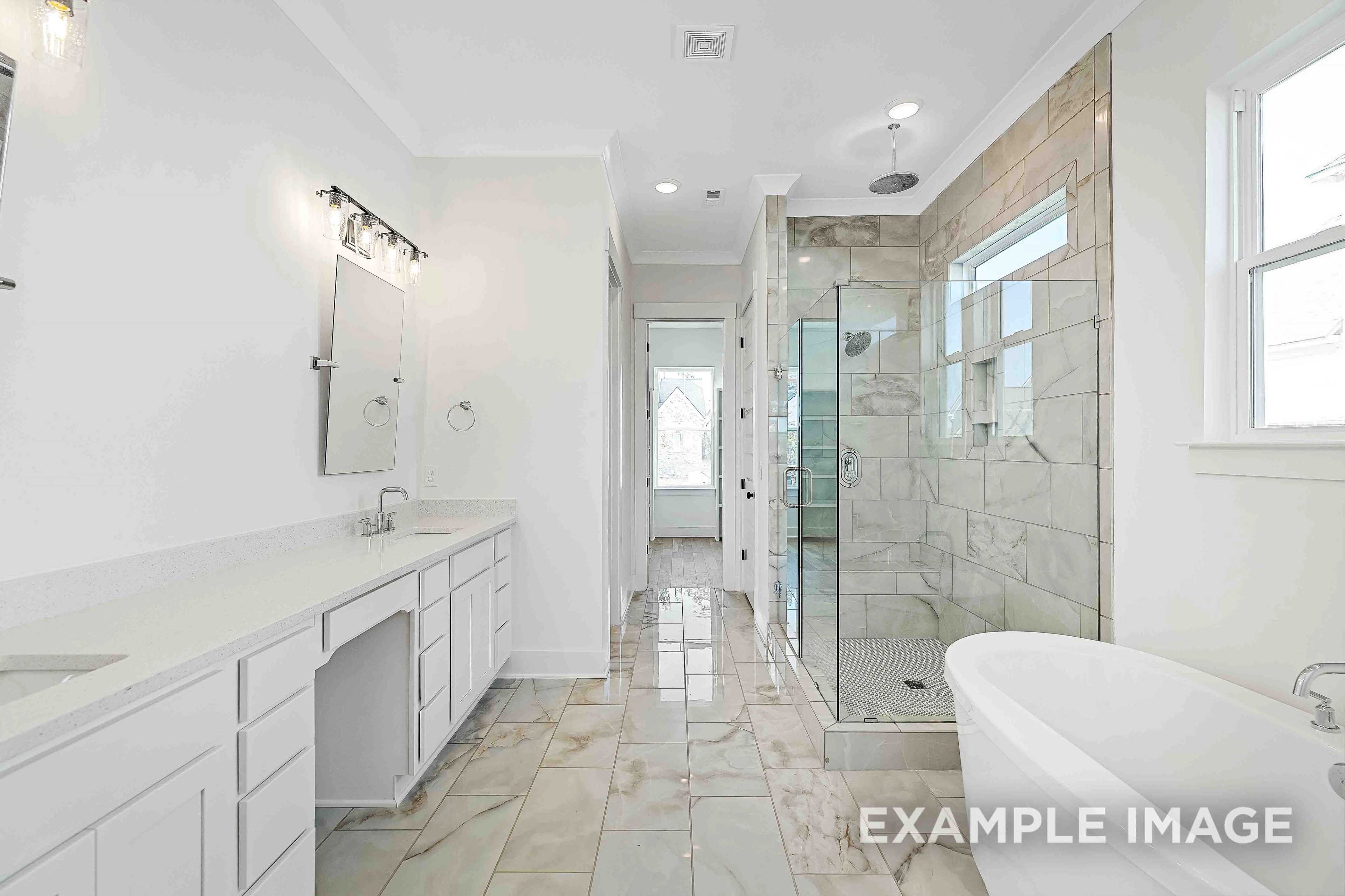 Spacious master bathroom in The Albany A featuring double vanity, freestanding tub, and glass-enclosed shower with stone tiles
