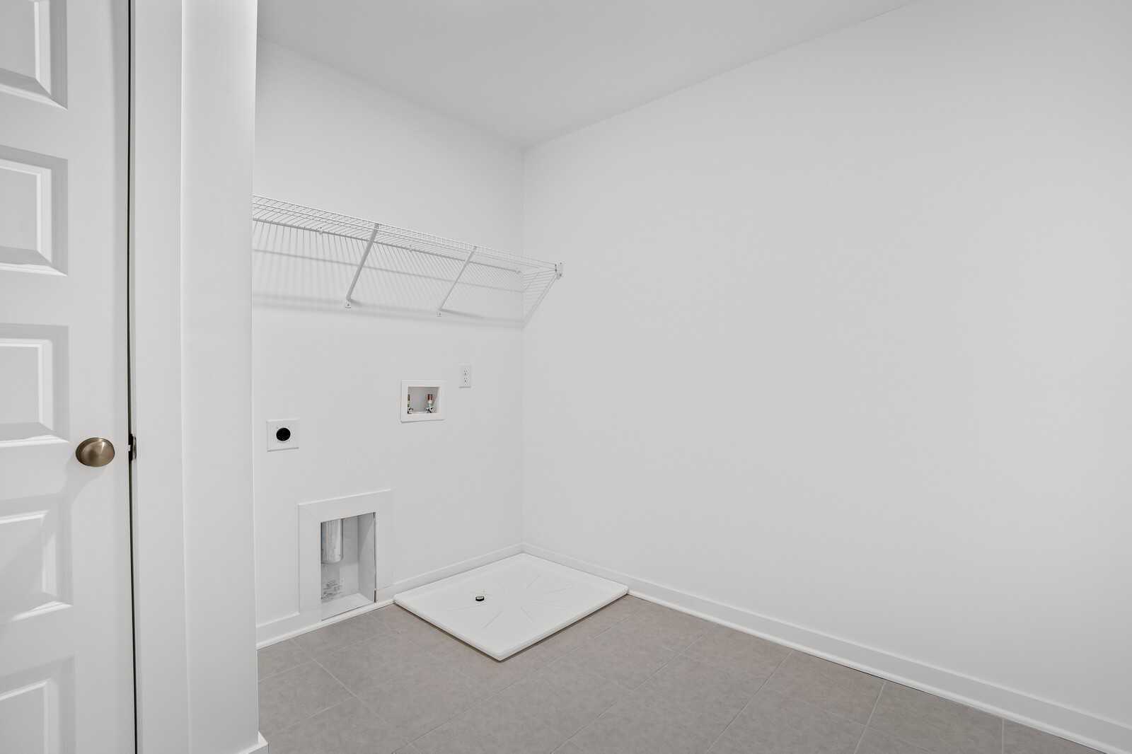 Bright white laundry room with wire shelving, washer/dryer hookups, utility sink in Davidson Homes The Logan C, Sage Farms, White House, TN