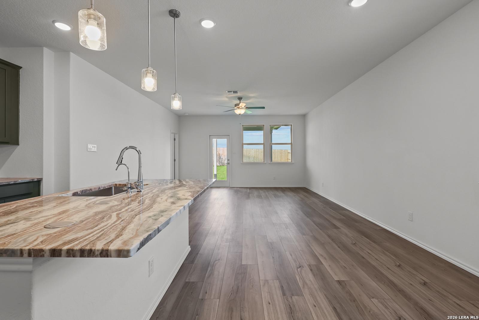 Open-concept kitchen and living area with stone island countertop in The Brazos B floor plan at Agave, San Antonio, Texas.