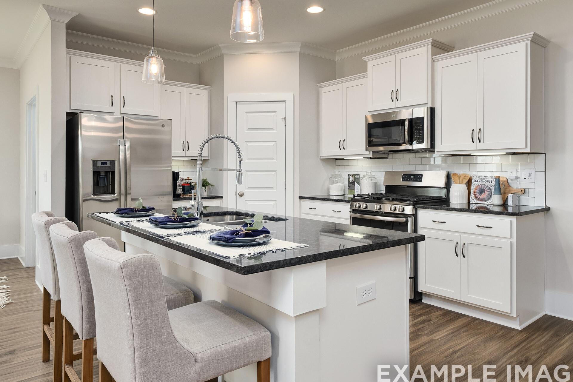 Modern kitchen in The Daphne D featuring white shaker cabinets, black granite island with seating, and stainless steel appliances