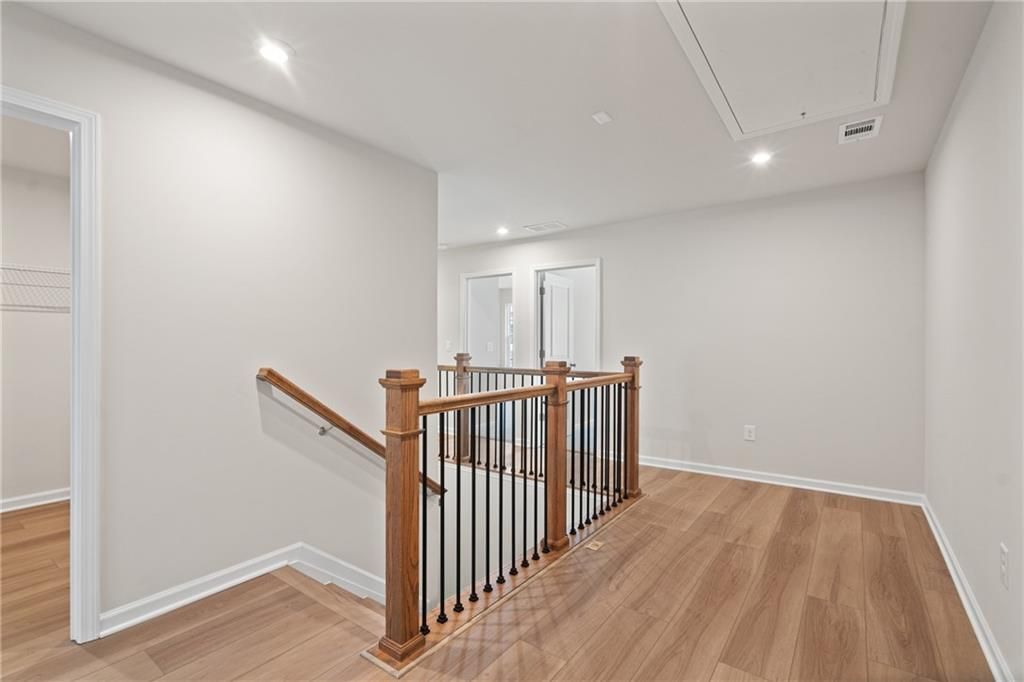 Bright upstairs hallway with wooden staircase railing, black balusters, and hardwood floors in Davidson Homes The Marion B, Kennesaw, GA