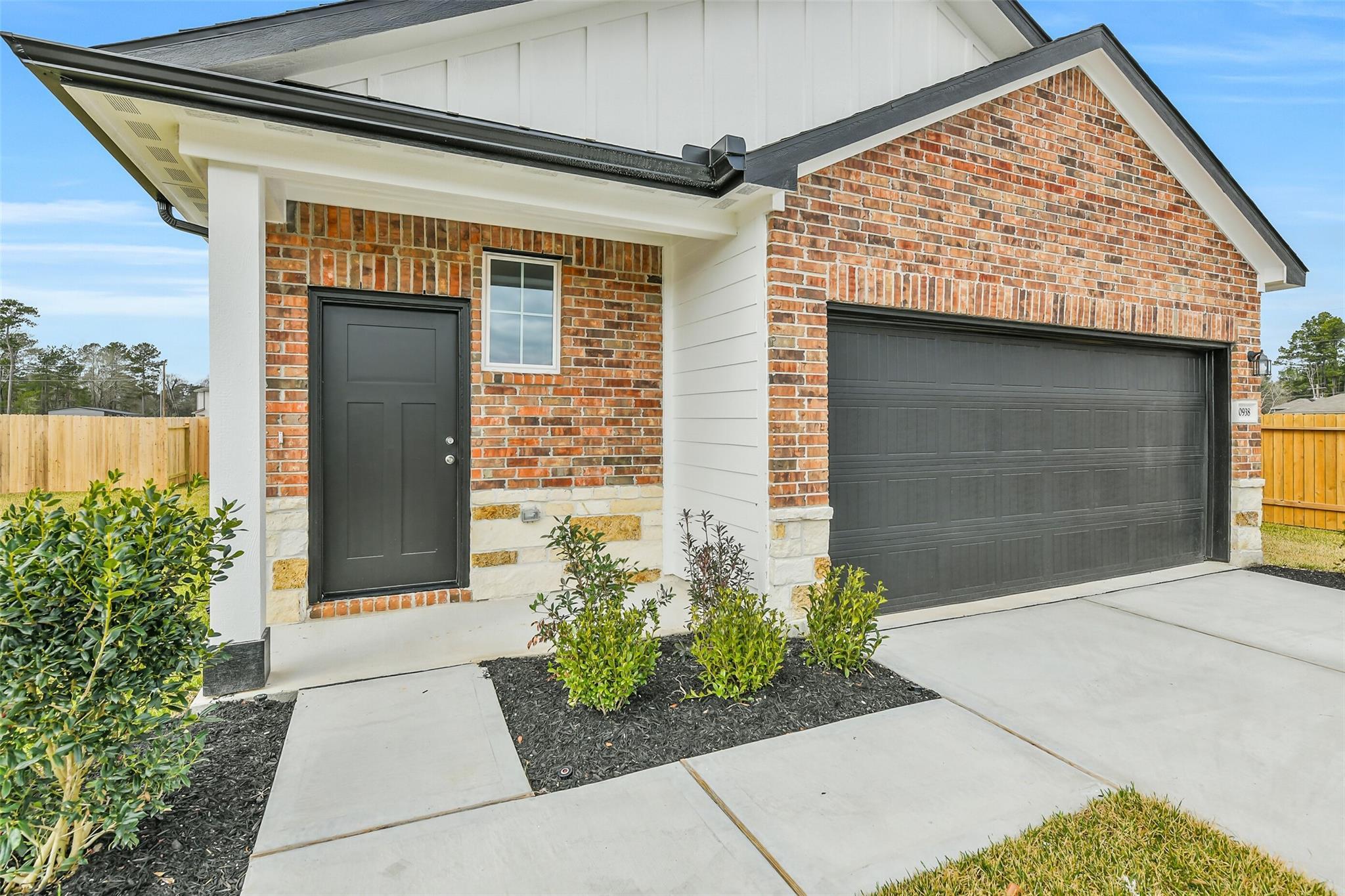 Front exterior of 3-bedroom Davidson Homes The Frio G: brick facade, black door, 2-car garage, covered porch in Cleveland, Texas