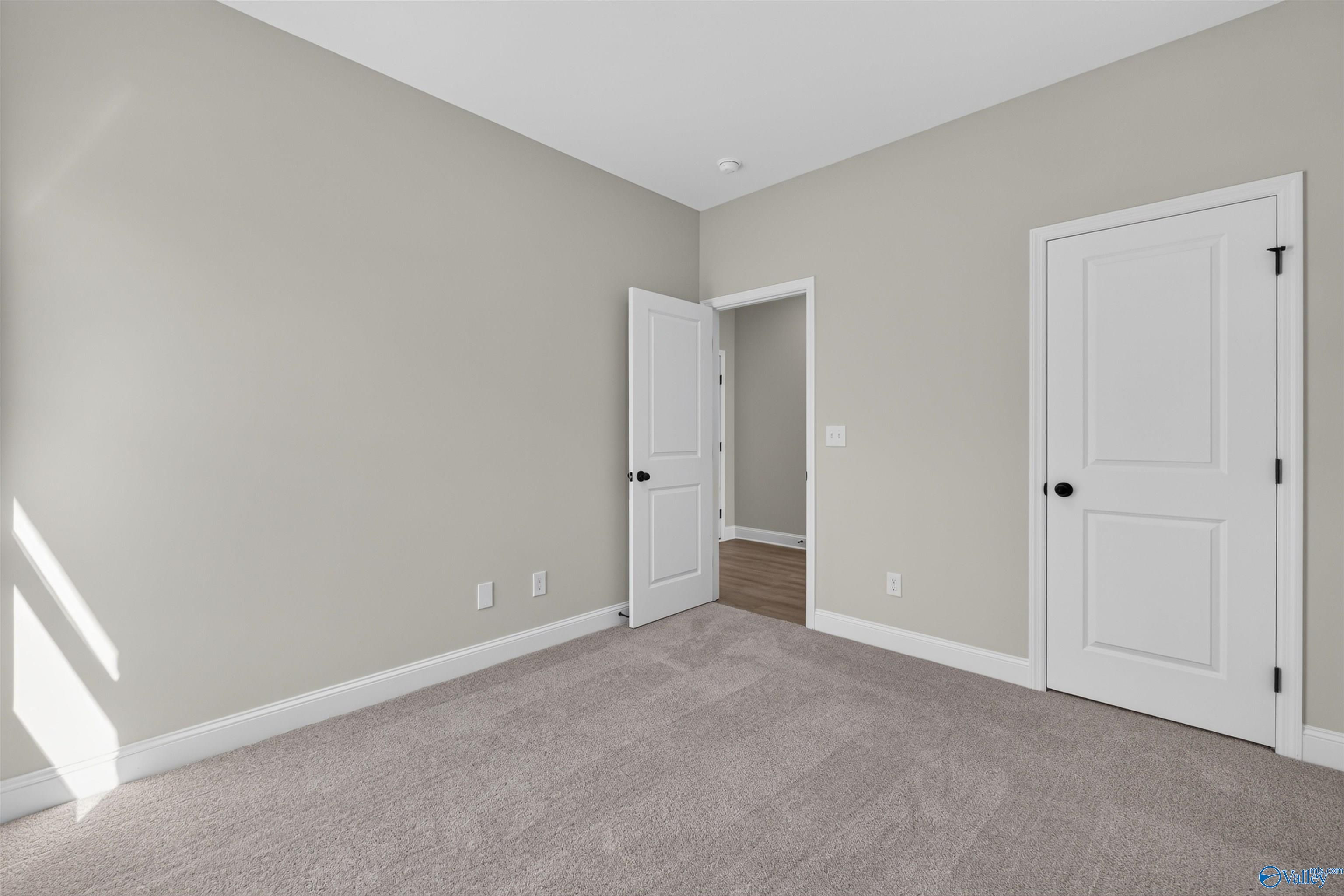 Bright carpeted bedroom with white doors and neutral walls in Davidson Homes The Butler floor plan, Hazel Green, Alabama
