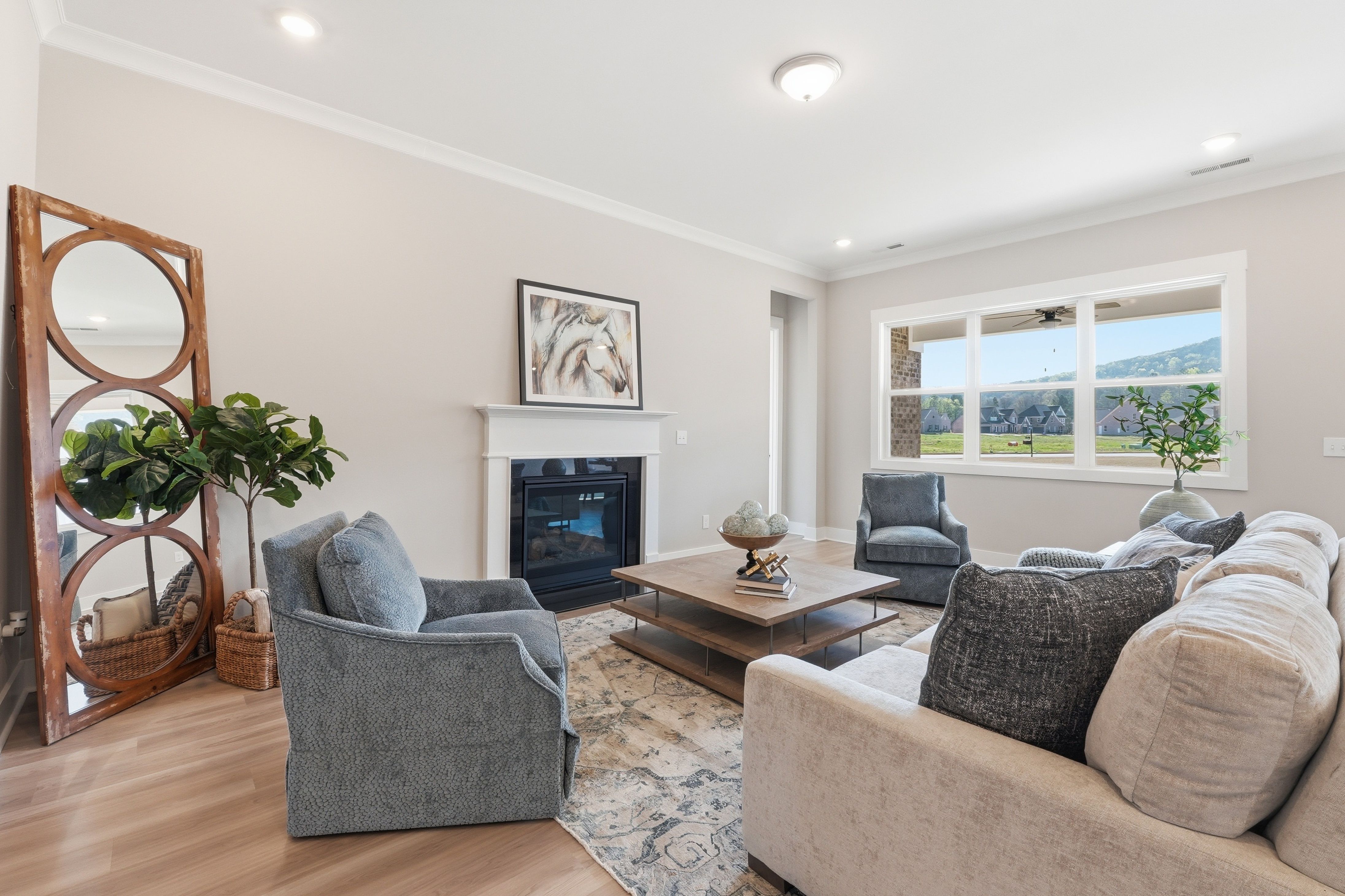 Open-concept living room at The Meadows at Hampton Cove in Owens Cross Roads AL featuring hardwood floors, fireplace, and mountain-view windows