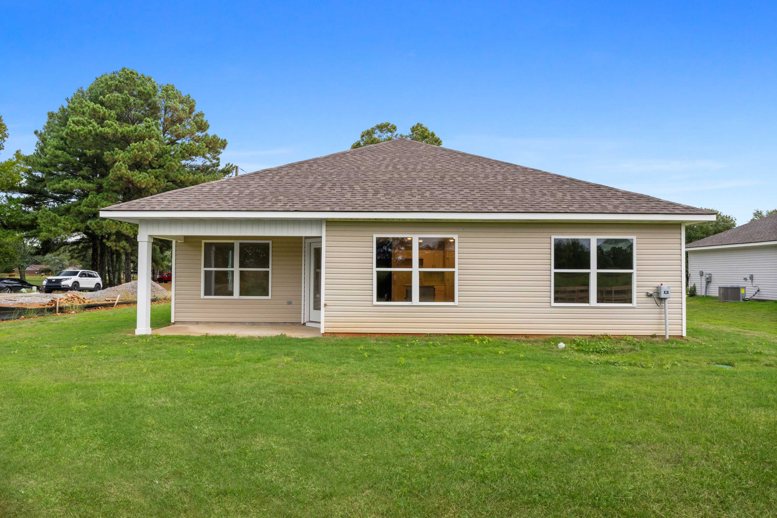 Ranch-style home exterior at Collins Lane in Meridianville Alabama with covered side porch, beige siding and green lawn