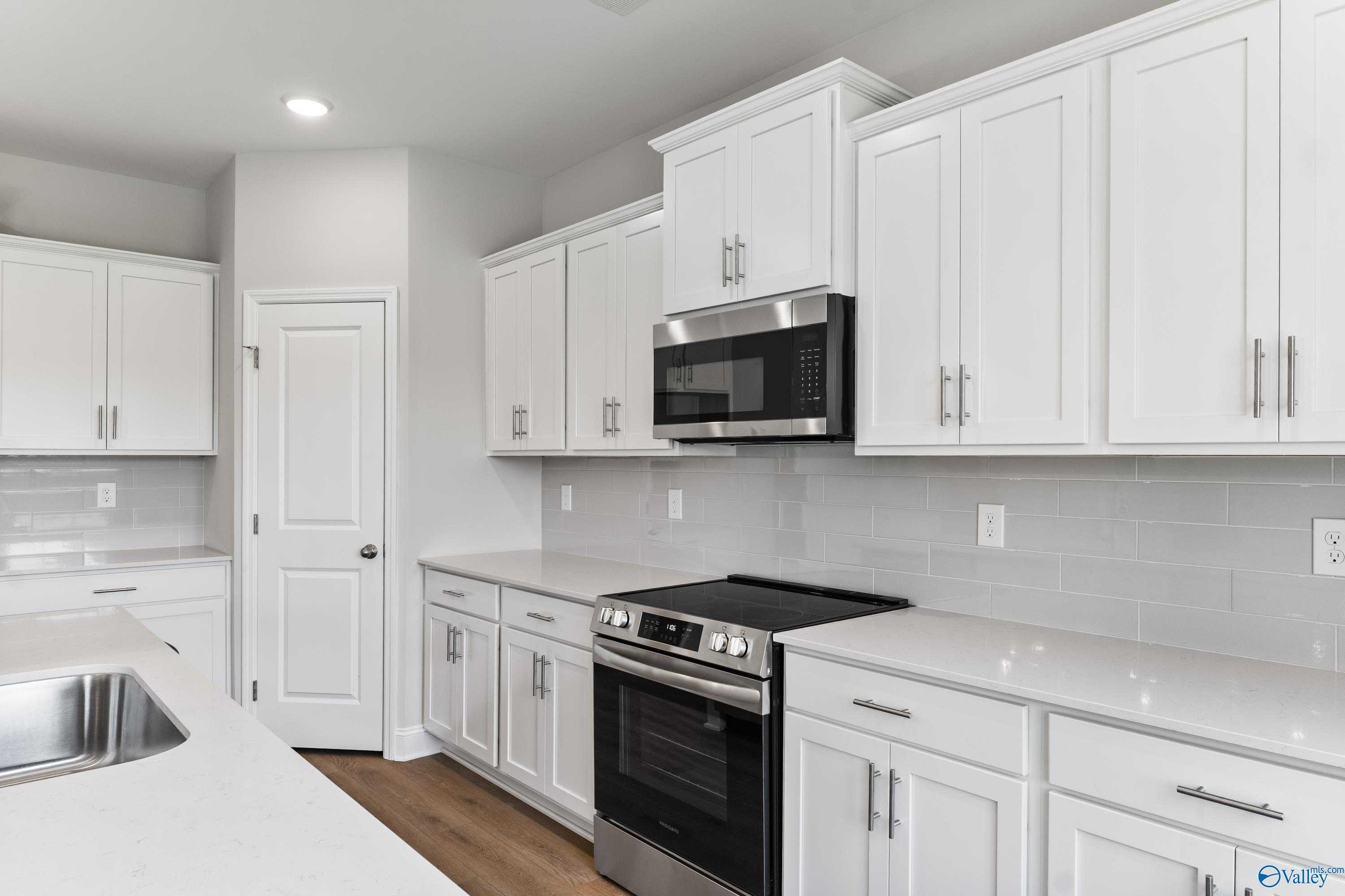 Modern white kitchen with stainless steel appliances, subway tile backsplash, and quartz counters in Davidson Homes Madison A, Toney, AL