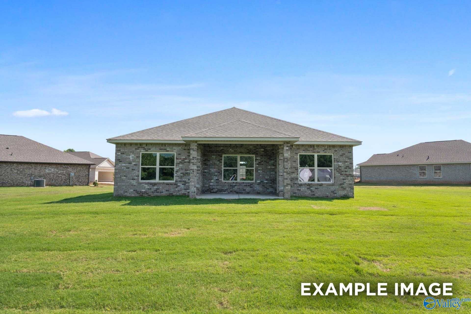 Modern single-story 3-bedroom home with stone facade, covered porch, and lush green lawn in The Highlands, Arab, Alabama by Davidson Homes The Asheville