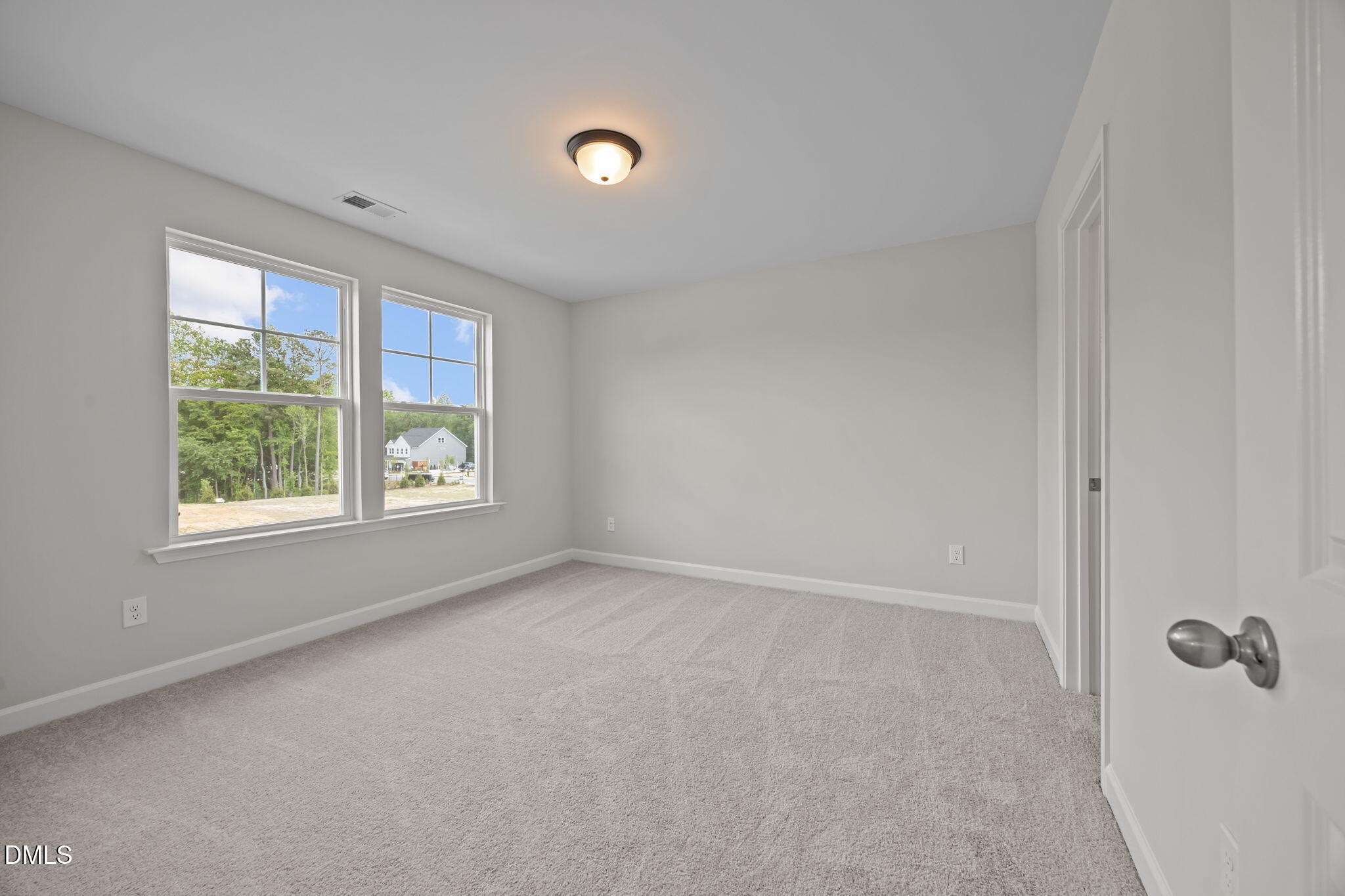 Bright empty bedroom with large windows, gray walls, carpeted floor in Davidson Homes The Willow D, Wendell, NC