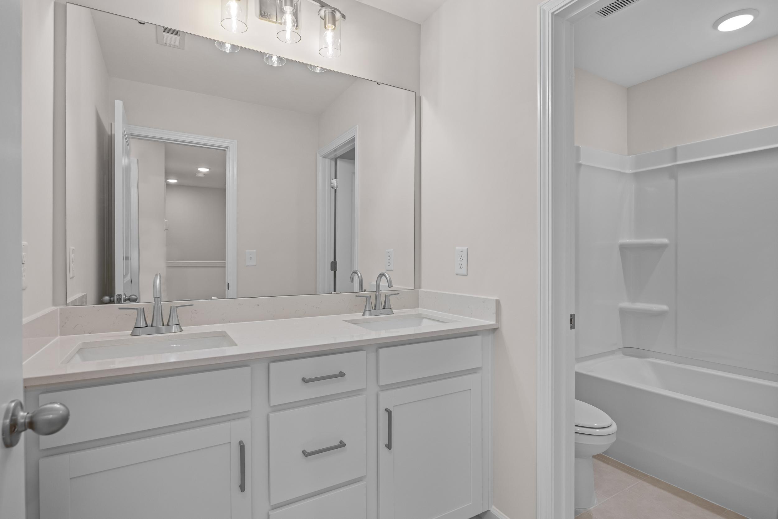 Spacious modern bathroom with double vanity, walk-in shower, and tub at Forestville Yard Townhomes in Knightdale, North Carolina