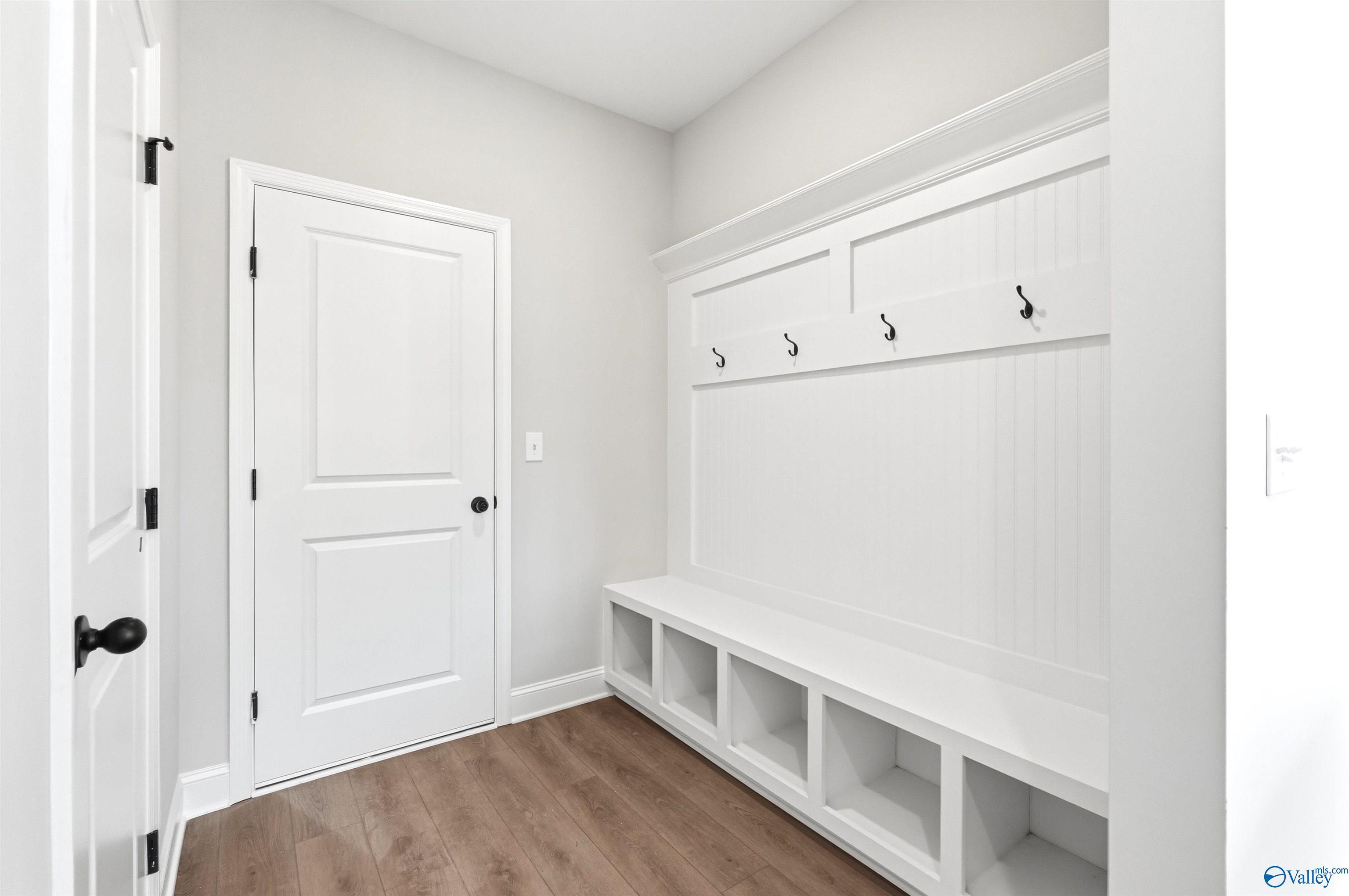 White mudroom bench with coat hooks and storage cubbies in The Chelsea D floor plan by Davidson Homes, New Market, AL.