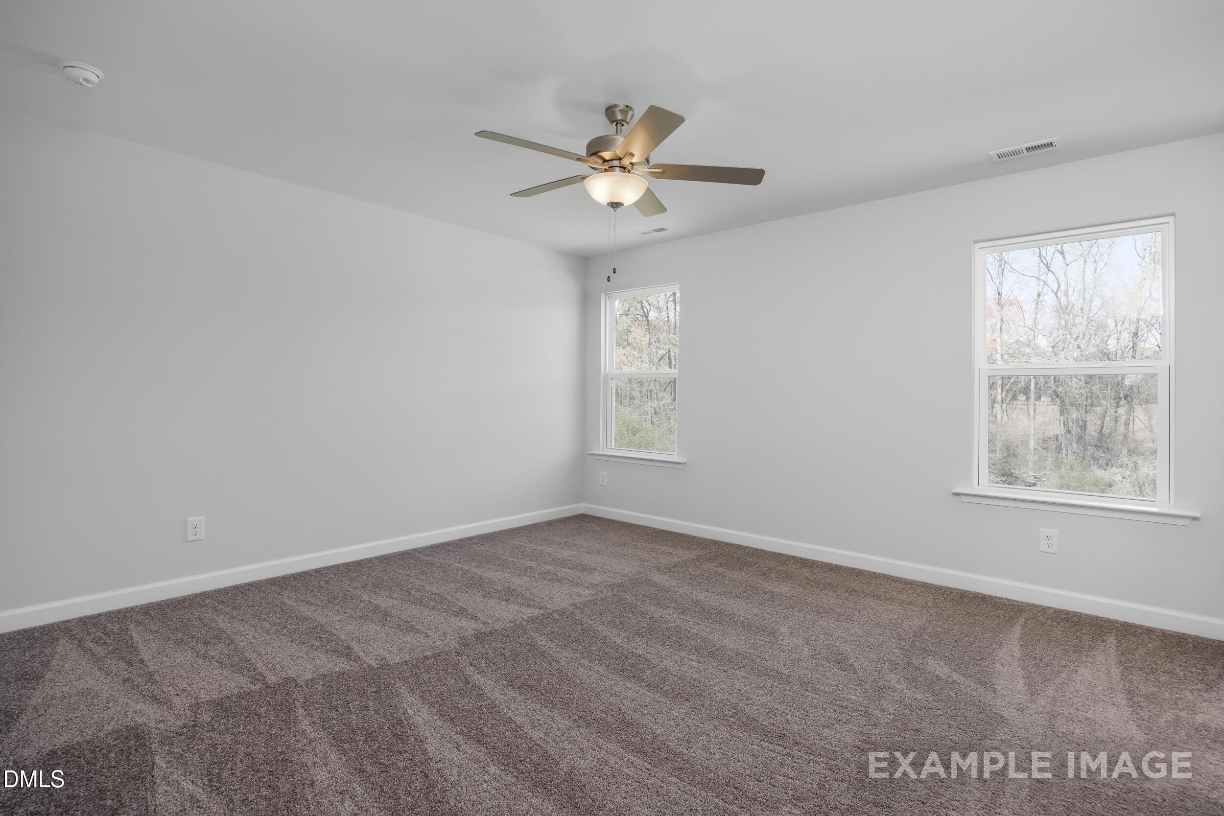Spacious bedroom with grey carpet and ceiling fan in The Gavin A floor plan by Davidson Homes in Gregory Village, Lillington.