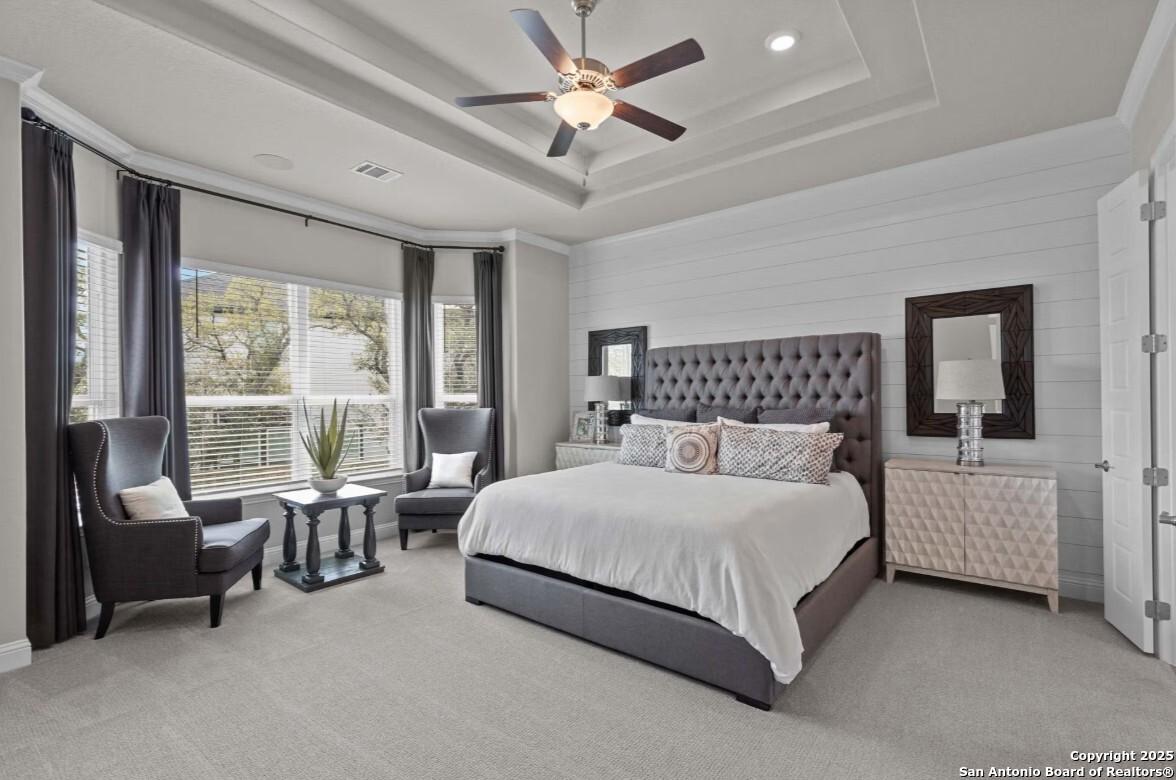Elegant master bedroom with gray upholstered king bed, ceiling fan, and bay windows in Davidson Homes The Garner B, San Antonio