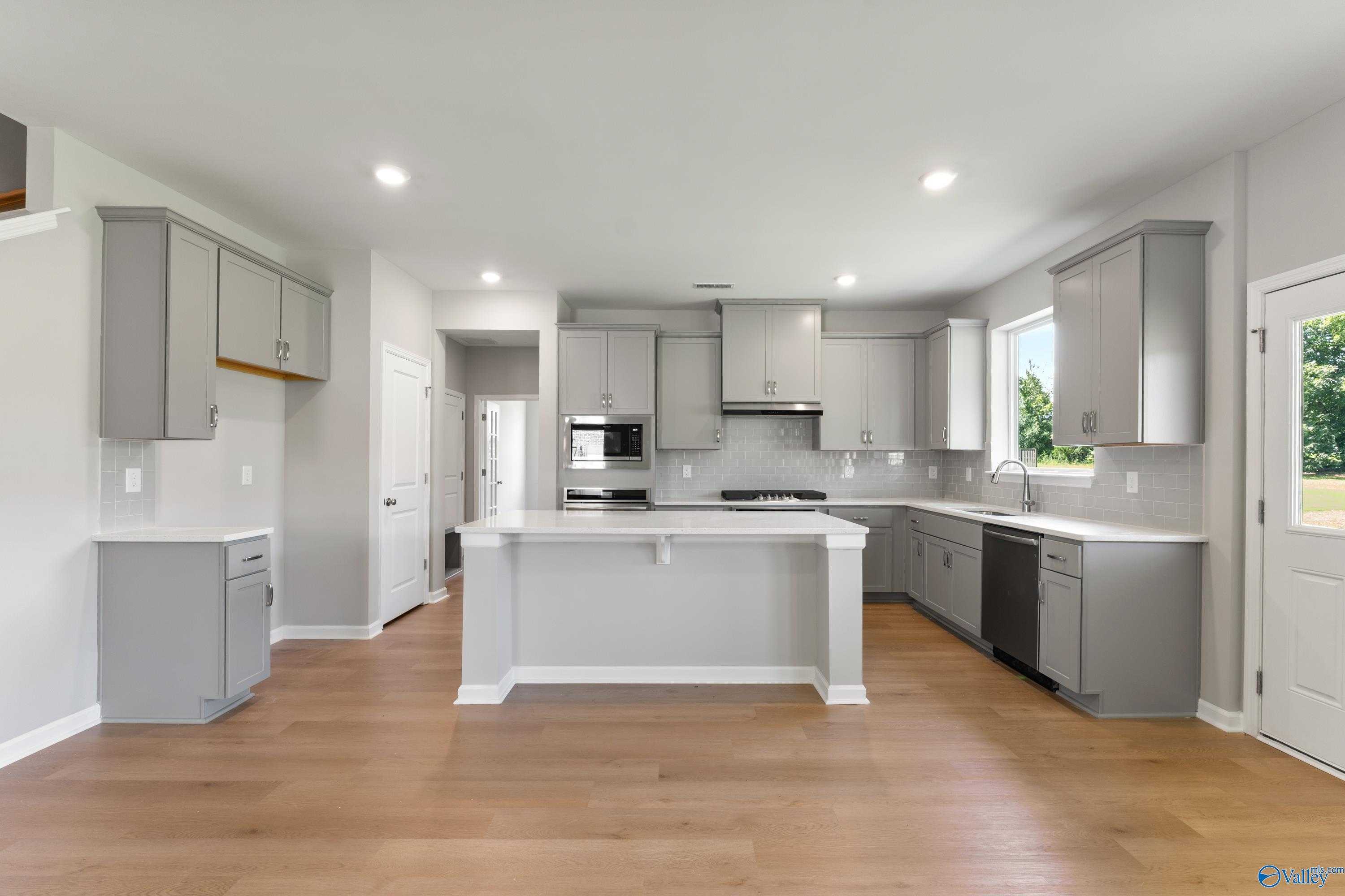 Modern gray cabinet kitchen with large white island, stainless appliances in Davidson Homes The Charm, Huntsville, AL