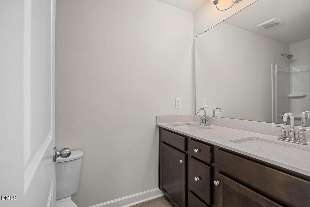 Modern bathroom with double vanity, dark wood cabinets, and large mirror in The Grace C floor plan, Retreat at North Main.
