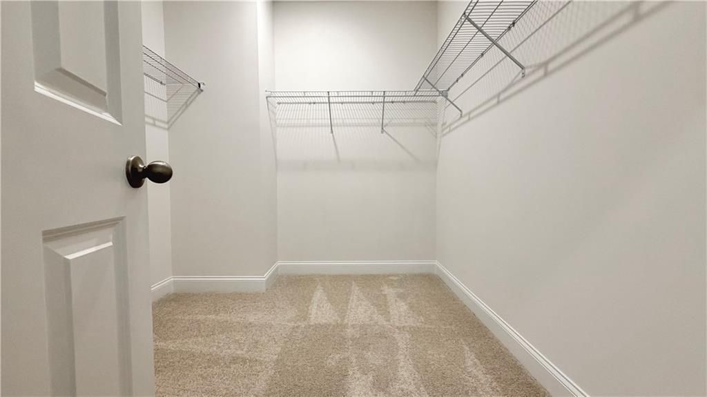 Spacious walk-in closet with wire shelving in The Glenwood A floor plan at Wehunt Meadows, Hoschton, GA.