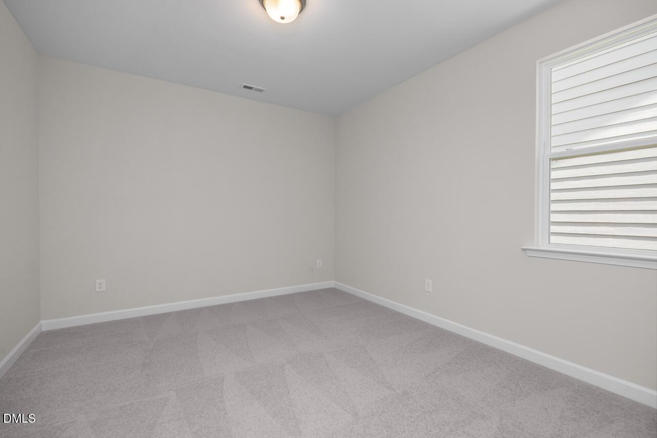 Spacious bedroom with neutral carpet and walls in The Ashport G floor plan at Sage on North Main, Wake Forest, NC.