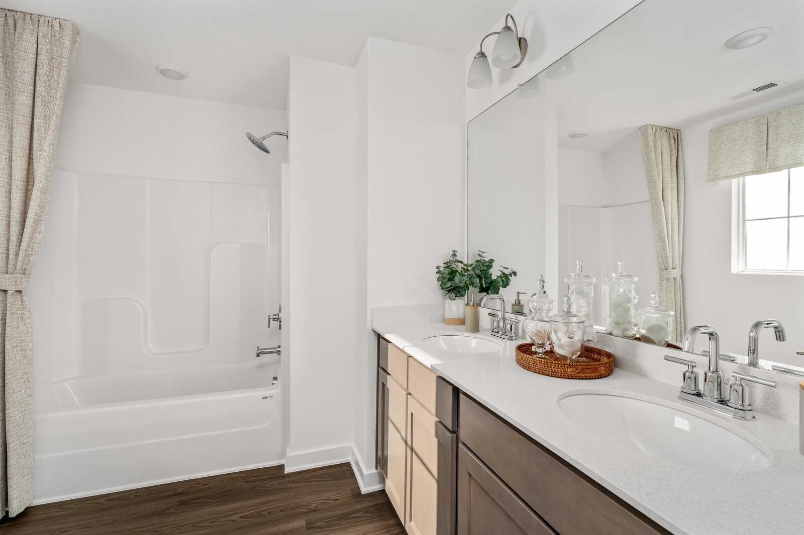 Modern bathroom with deep soaking tub, glass-enclosed shower, and quartz double vanity in Davidson Homes The Cumberland A, Gallatin, TN