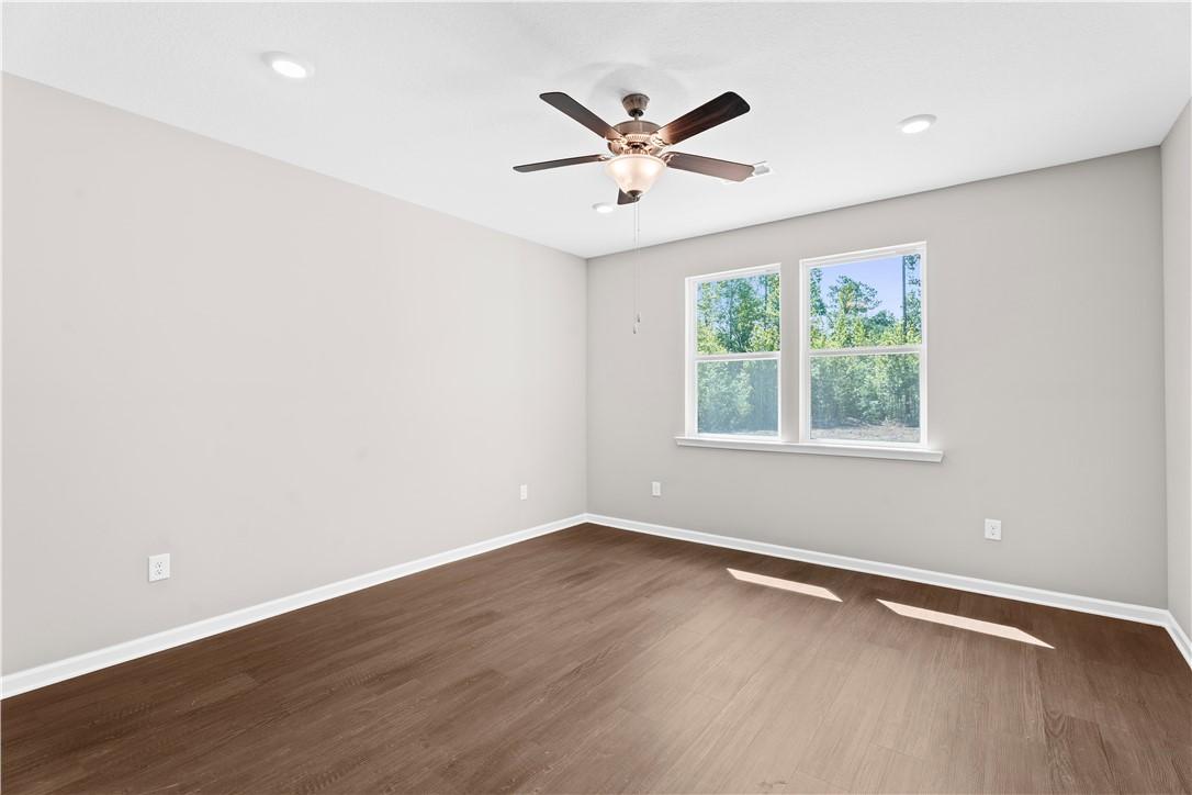Bright bedroom with gray walls, large windows, ceiling fan and hardwood floors in Evermore Homes The Orion, Cusseta, Alabama