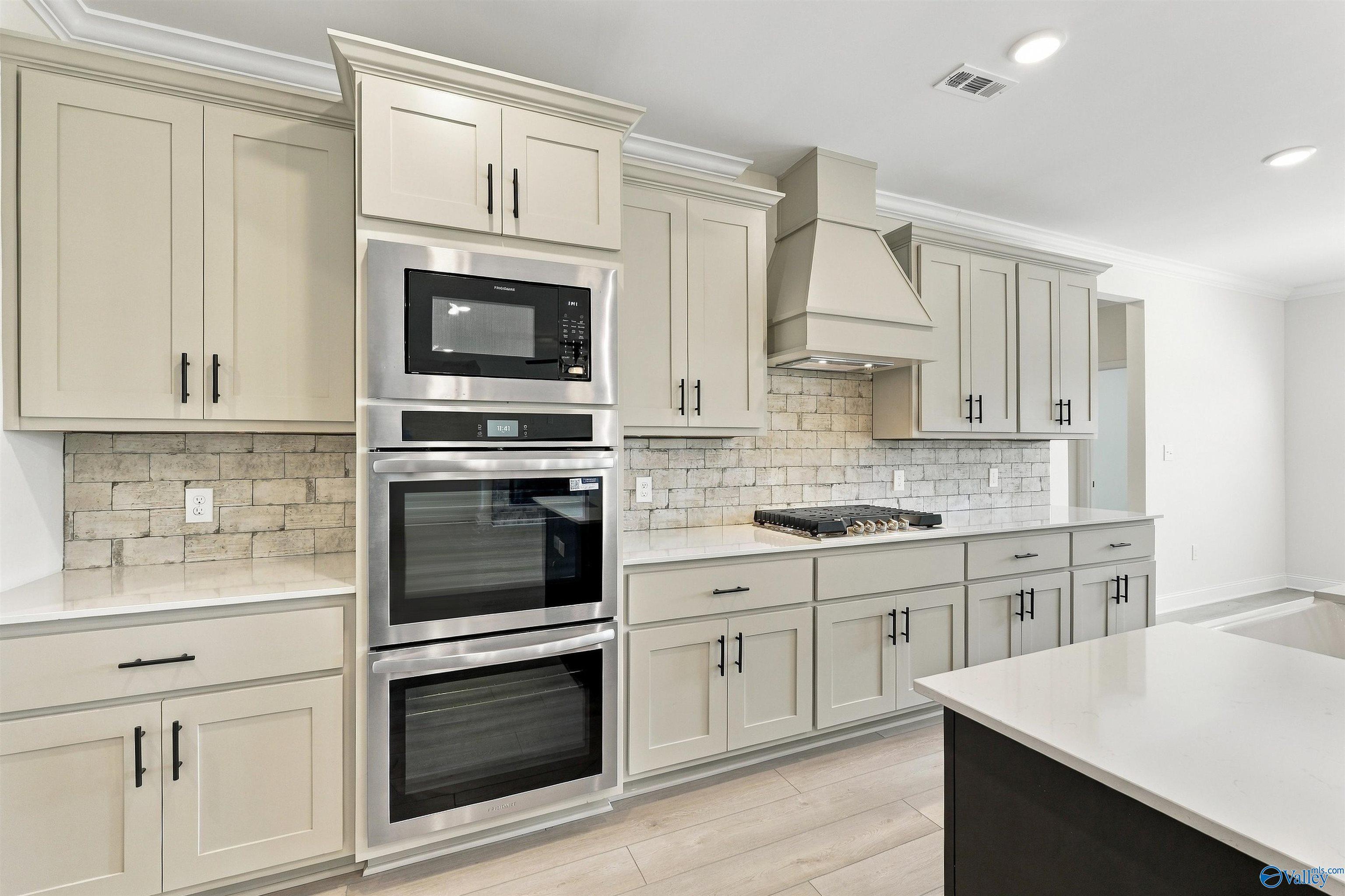 Modern kitchen with double ovens, gas cooktop, and cream shaker cabinets in Davidson Homes The Valencia, Huntsville, Alabama