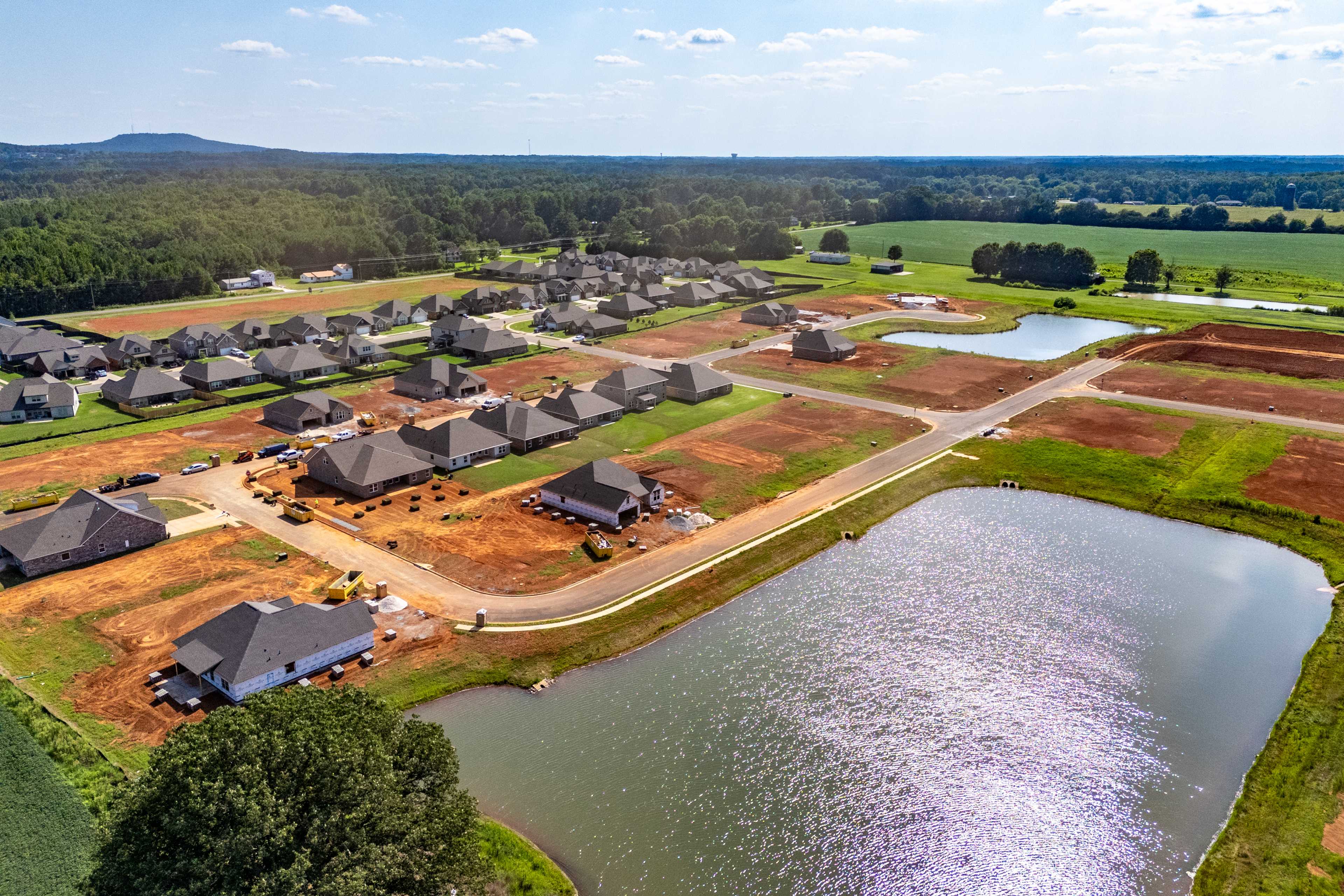 Aerial view of Kendall Downs in Toney Alabama featuring serene pond new homes construction sites and wooded hills by Davidson Homes