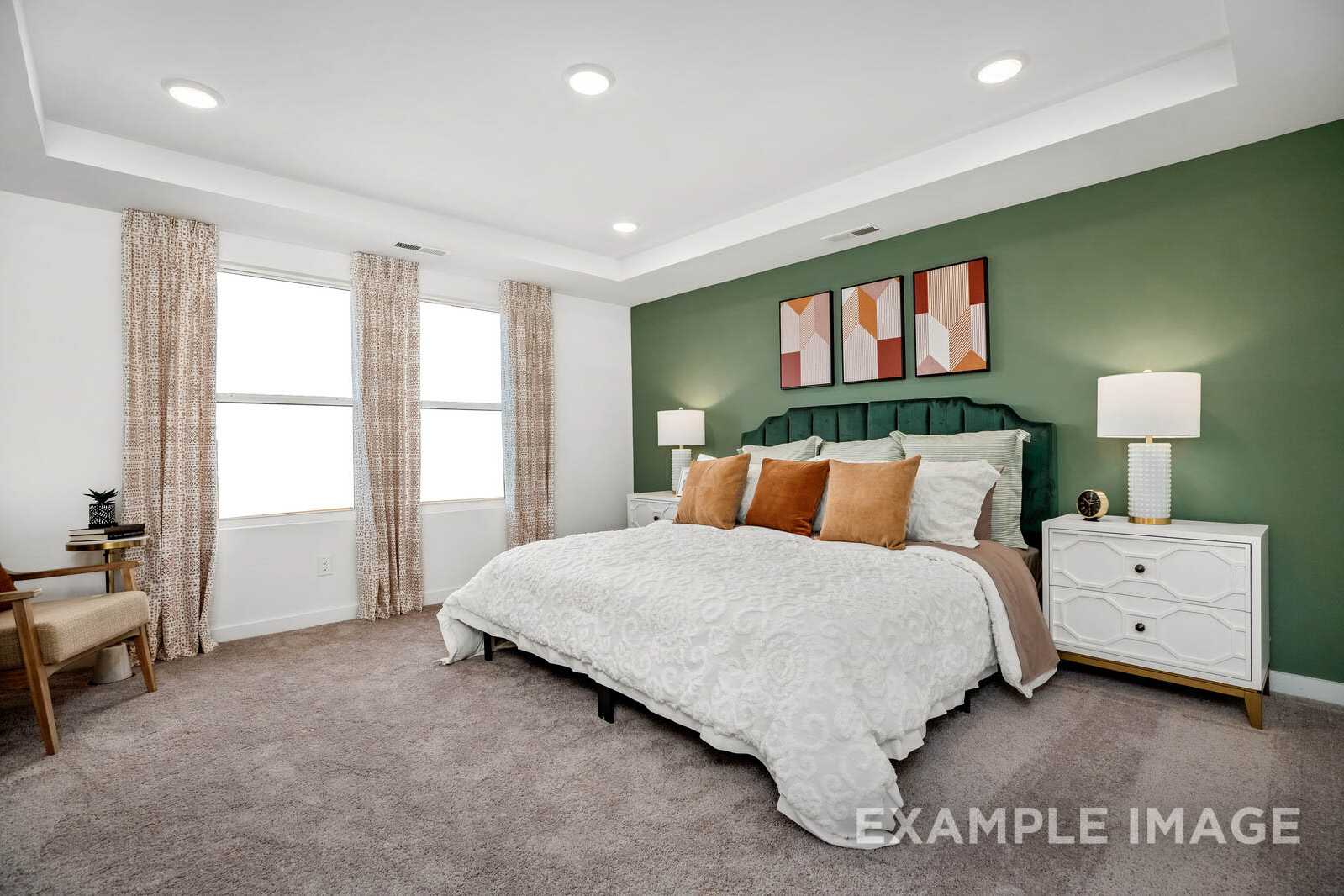 Spacious master bedroom in The Gordon B with green accent wall, king bed, orange pillows, and modern nightstands