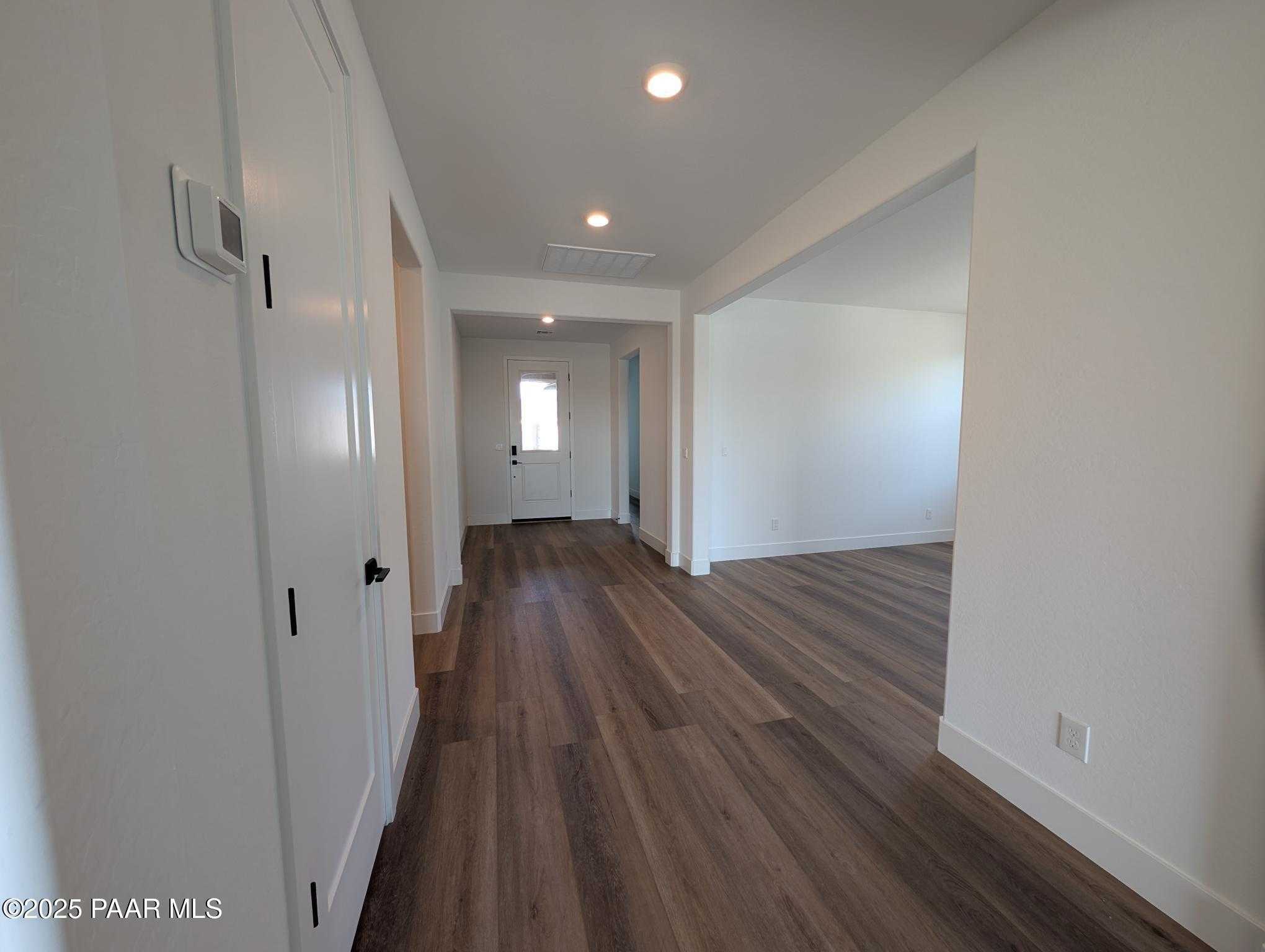 Bright entry hallway with luxury vinyl plank flooring, white doors, and recessed lights in The Sheridan II F home, Prescott, Arizona
