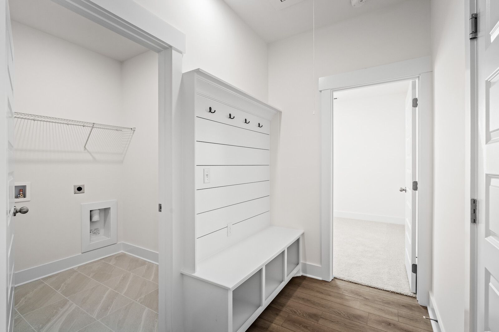 Mudroom entry with white shiplap bench and storage cubbies adjacent to the laundry room in The Cottonwood floor plan.