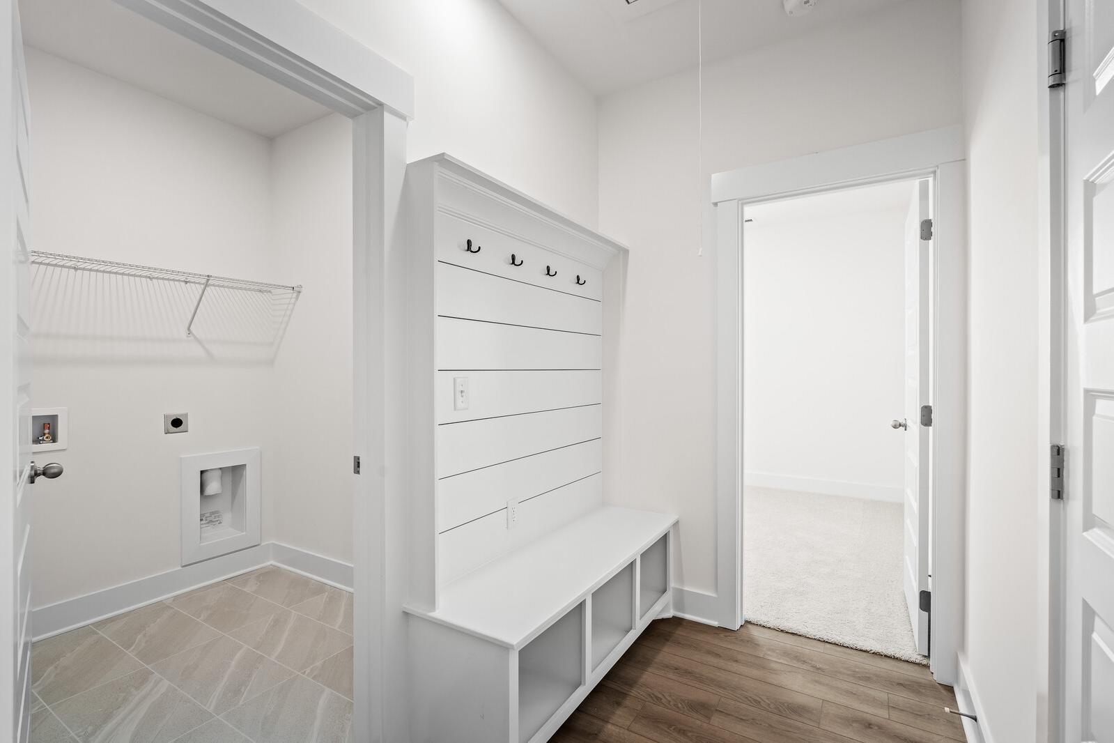 Mudroom entry with white shiplap bench and storage cubbies adjacent to the laundry room in The Cottonwood floor plan.