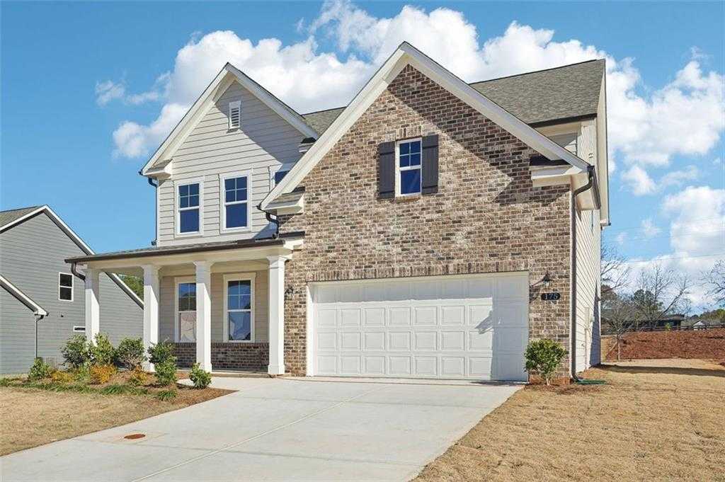 Two-story brick and siding home with covered front porch, two-car garage, and driveway in Wehunt Meadows, Hoschton, Georgia