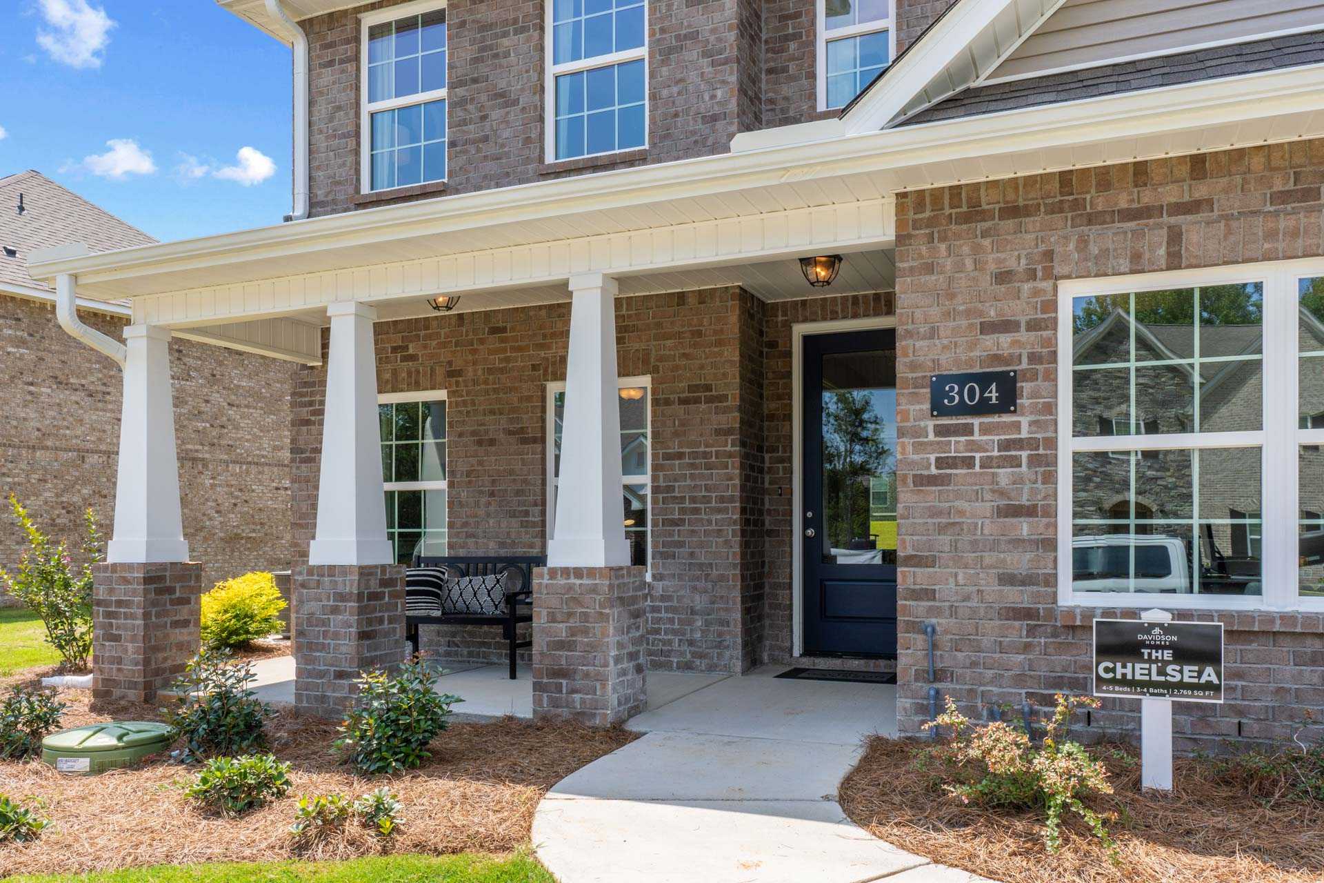 Chelsea model brick home exterior at Creek Grove in New Market Alabama with covered porch white columns and landscaped yard