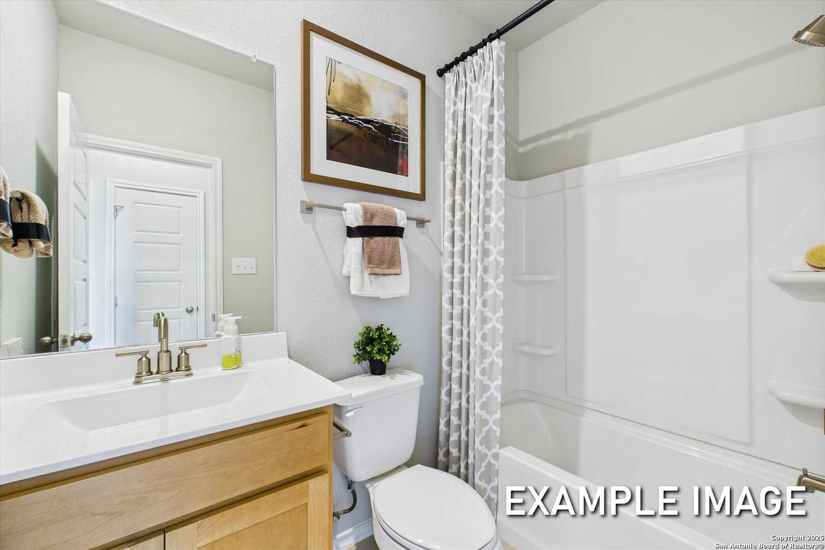 Spacious master bathroom with walk-in shower, soaking tub, oak vanity, and abstract wall art in Davidson Homes The Sabine C, Agave, San Antonio