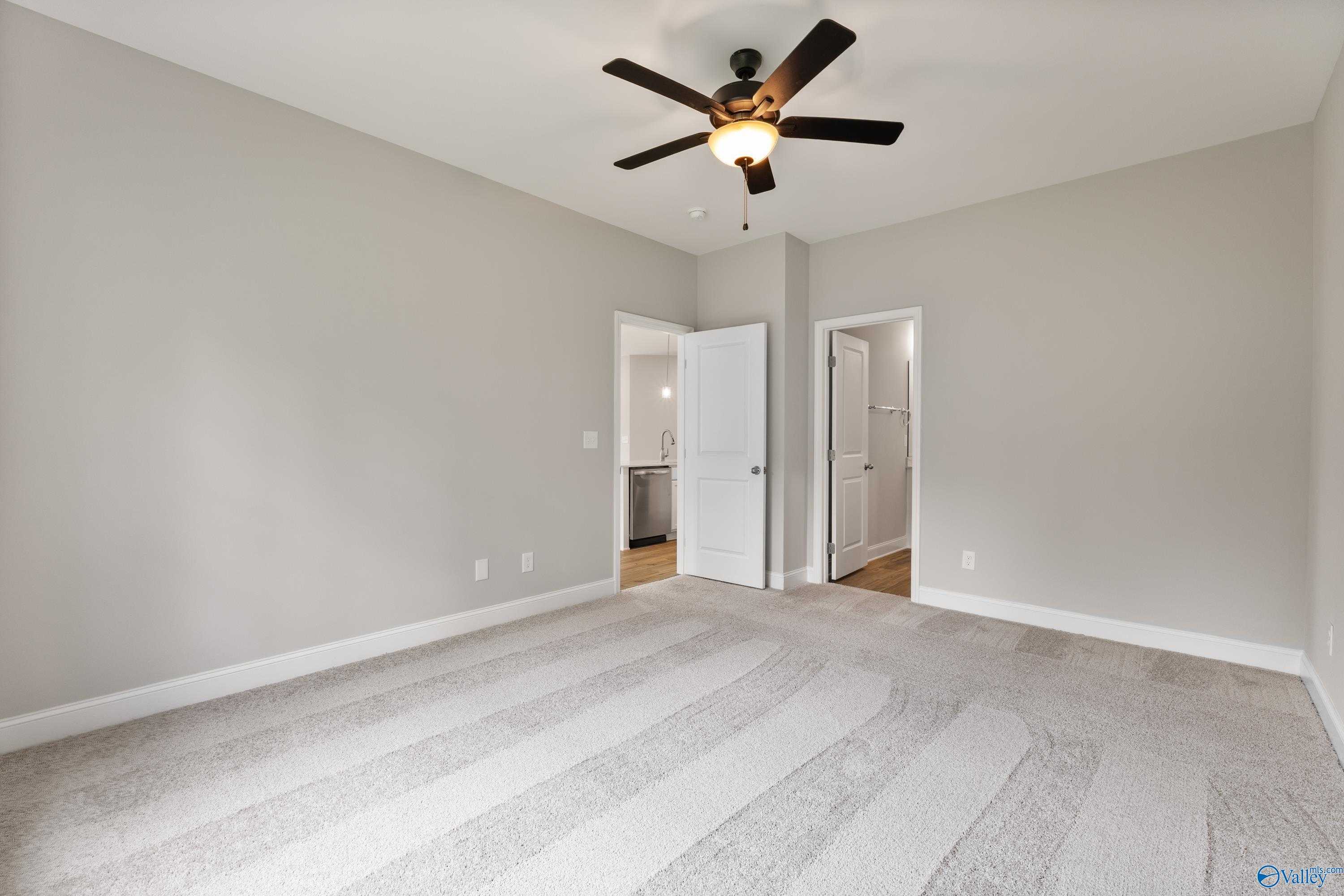 Bright secondary bedroom with gray walls, ceiling fan, carpet flooring, and bathroom access in Davidson Homes The Franklin, Huntsville AL