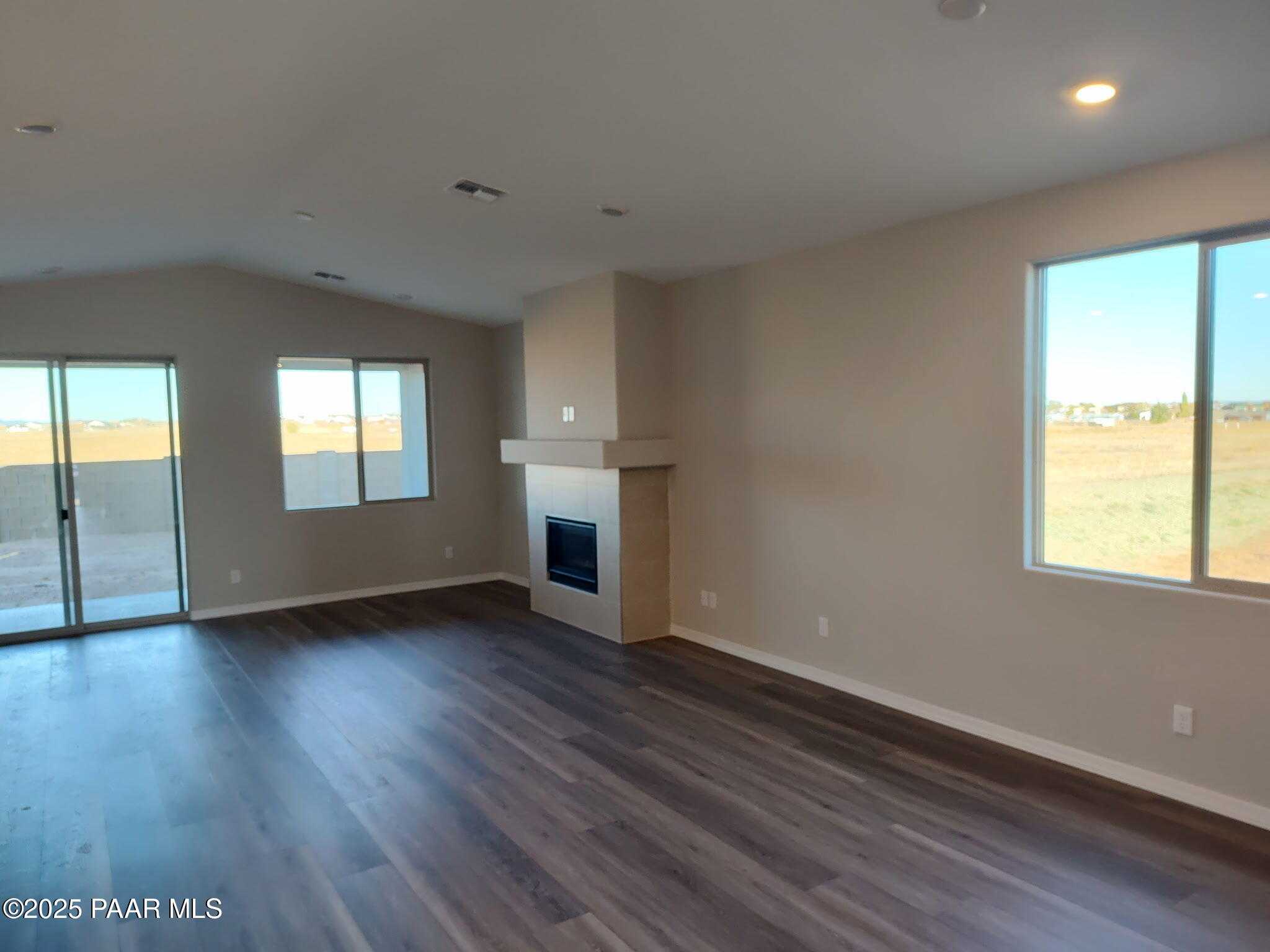 Spacious open living room with gas fireplace, sliding glass doors, and desert views in Davidson Homes The Frontier A, Prescott Valley, Arizona