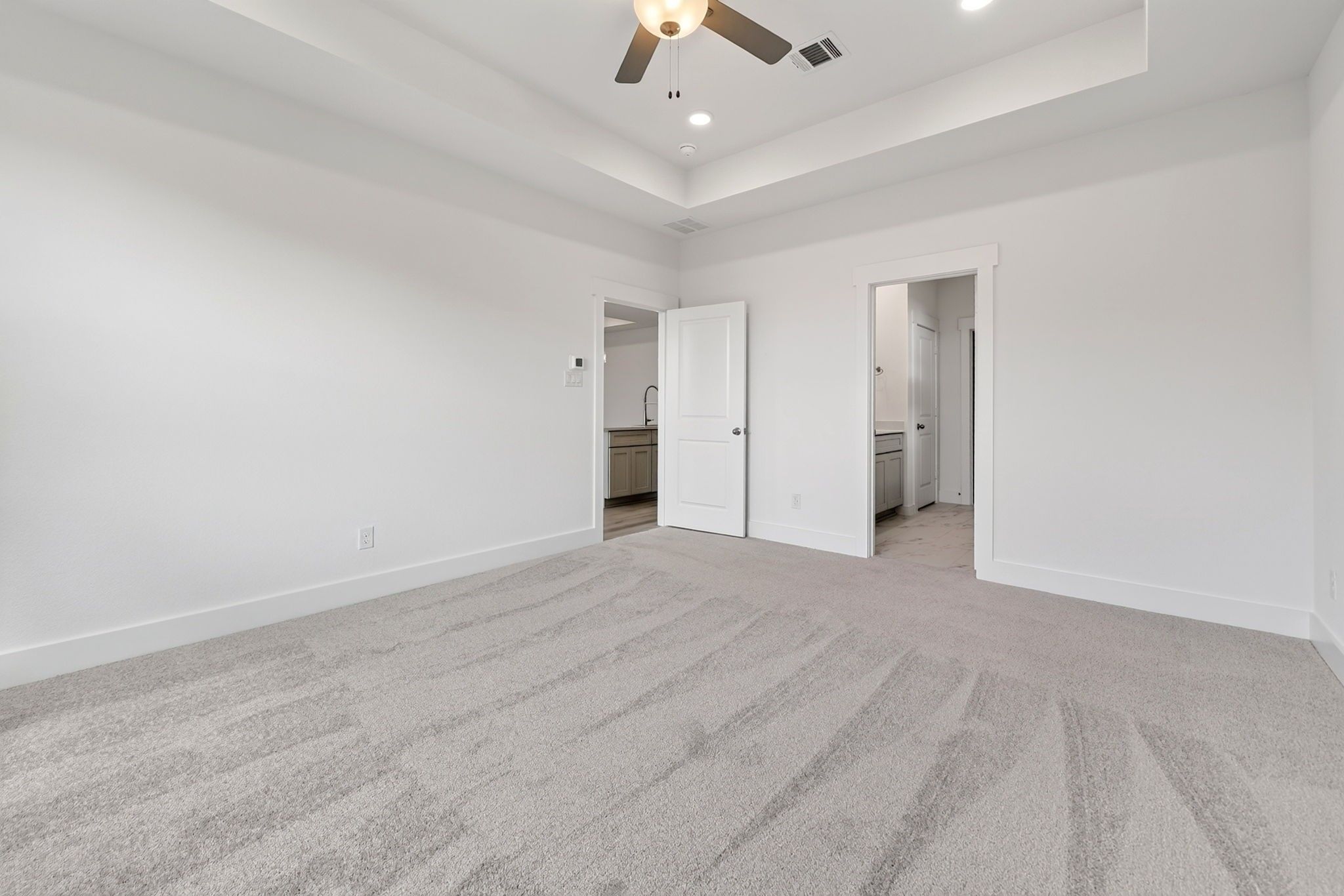 Spacious carpeted bedroom with tray ceiling and ceiling fan in Davidson Homes The Holly F, Meadow Ridge Estates, Josephine, Texas
