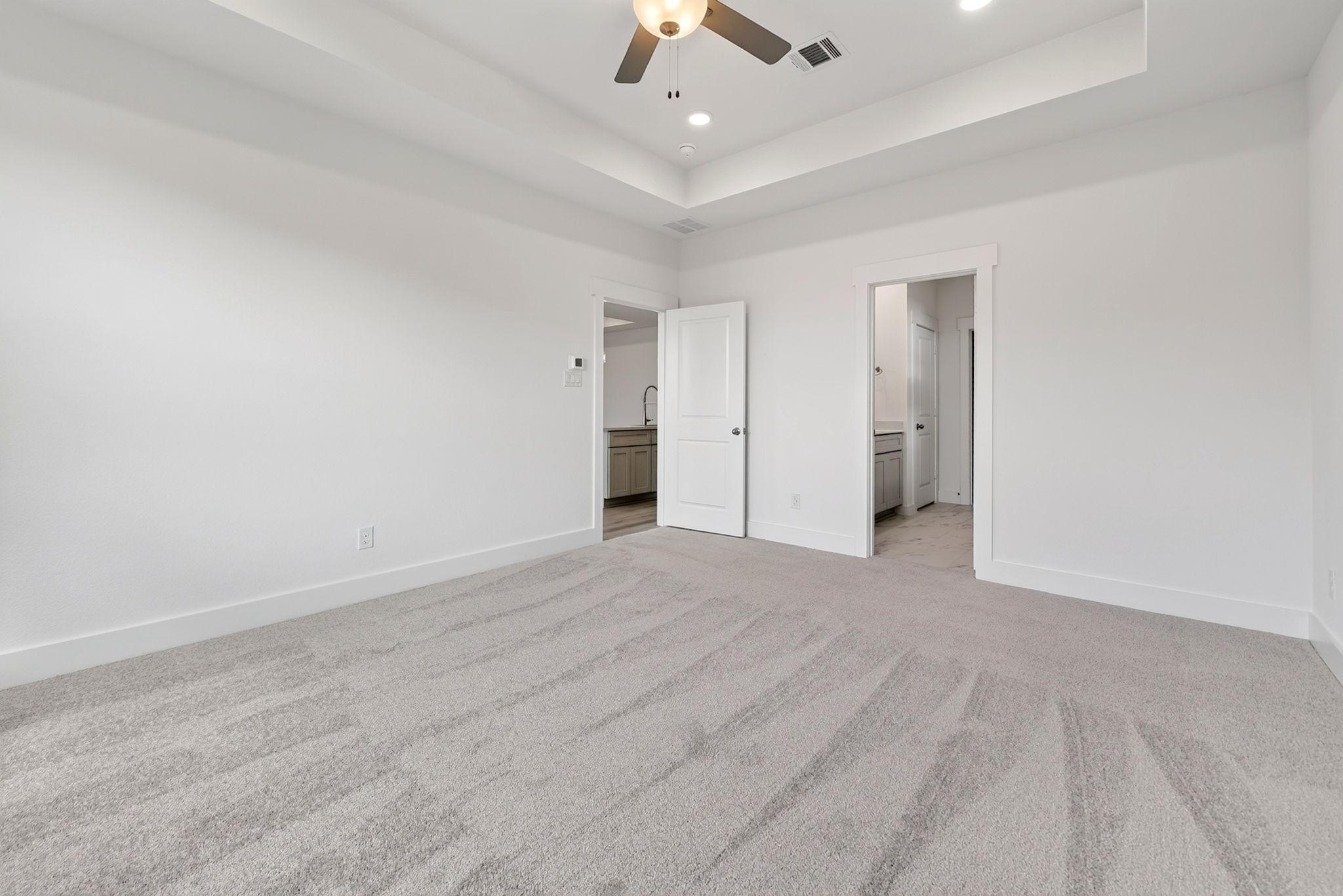 Spacious carpeted bedroom with tray ceiling and ceiling fan in Davidson Homes The Holly F, Meadow Ridge Estates, Josephine, Texas