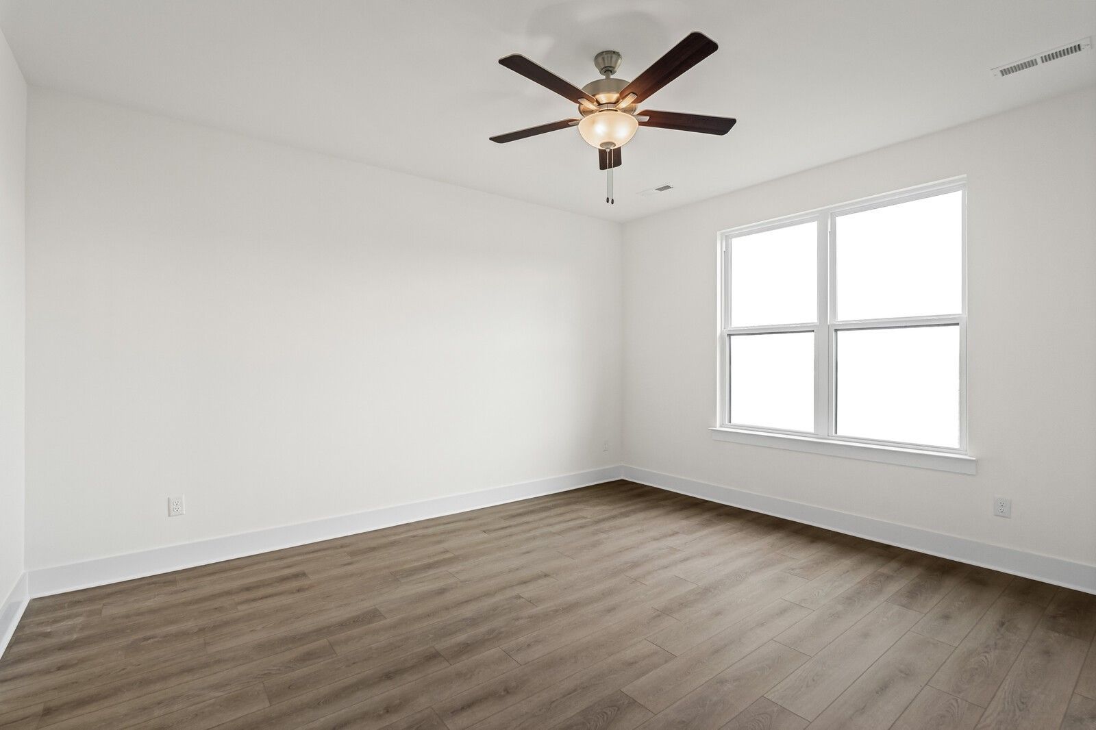 Bright empty bedroom featuring hardwood floors, ceiling fan with light, and large windows in Davidson Homes The Ridgeport D, Mt. Juliet
