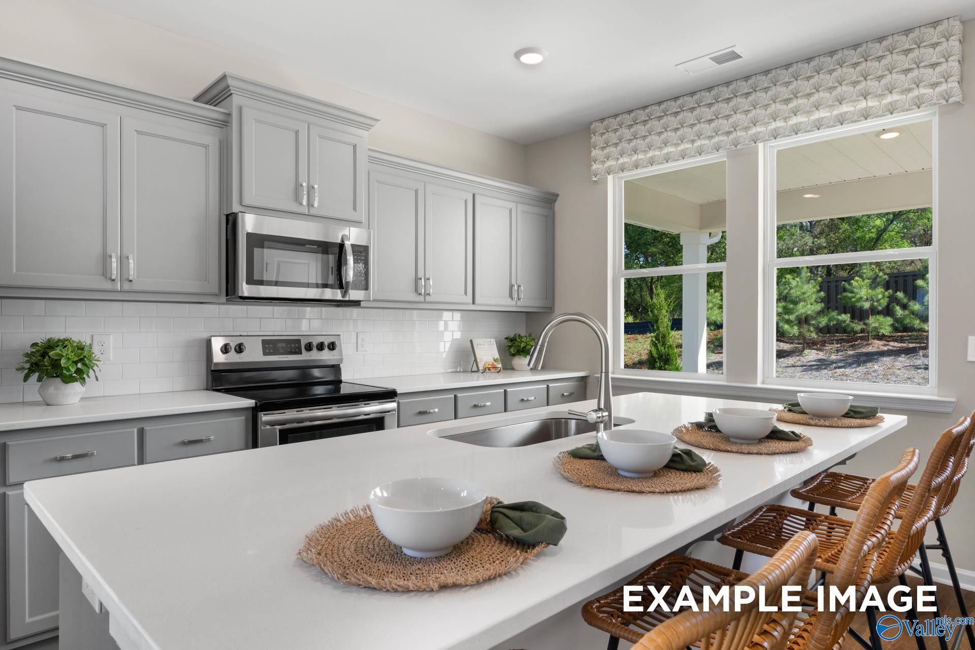 Modern kitchen with white shaker cabinets, stainless steel appliances, quartz island seating in Davidson Homes The Stella, Madison AL