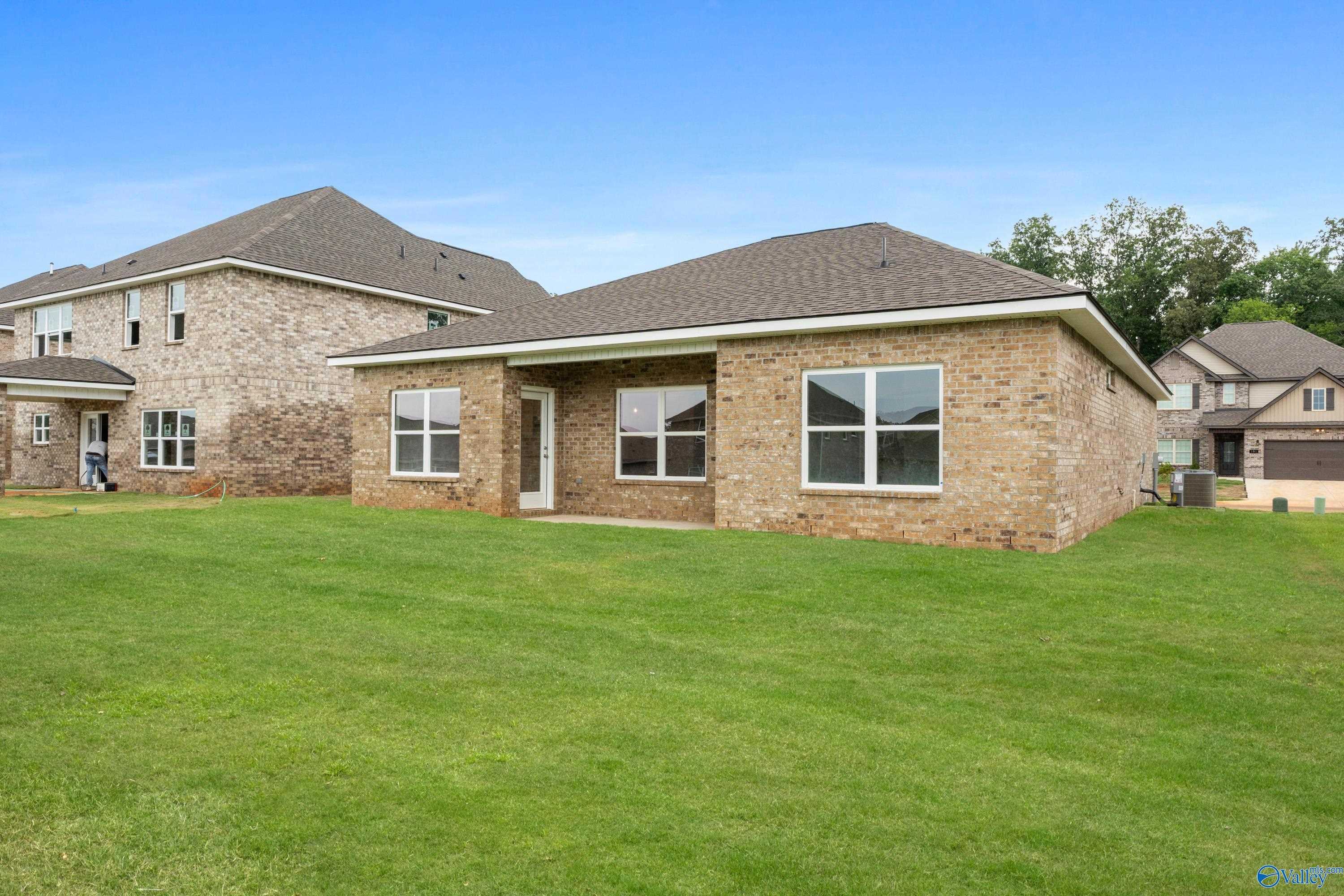 Brick single-story 3-bedroom home with 2-car garage and large windows on lush green lawn in Creek Grove, New Market, Alabama - Davidson Homes Asheville C