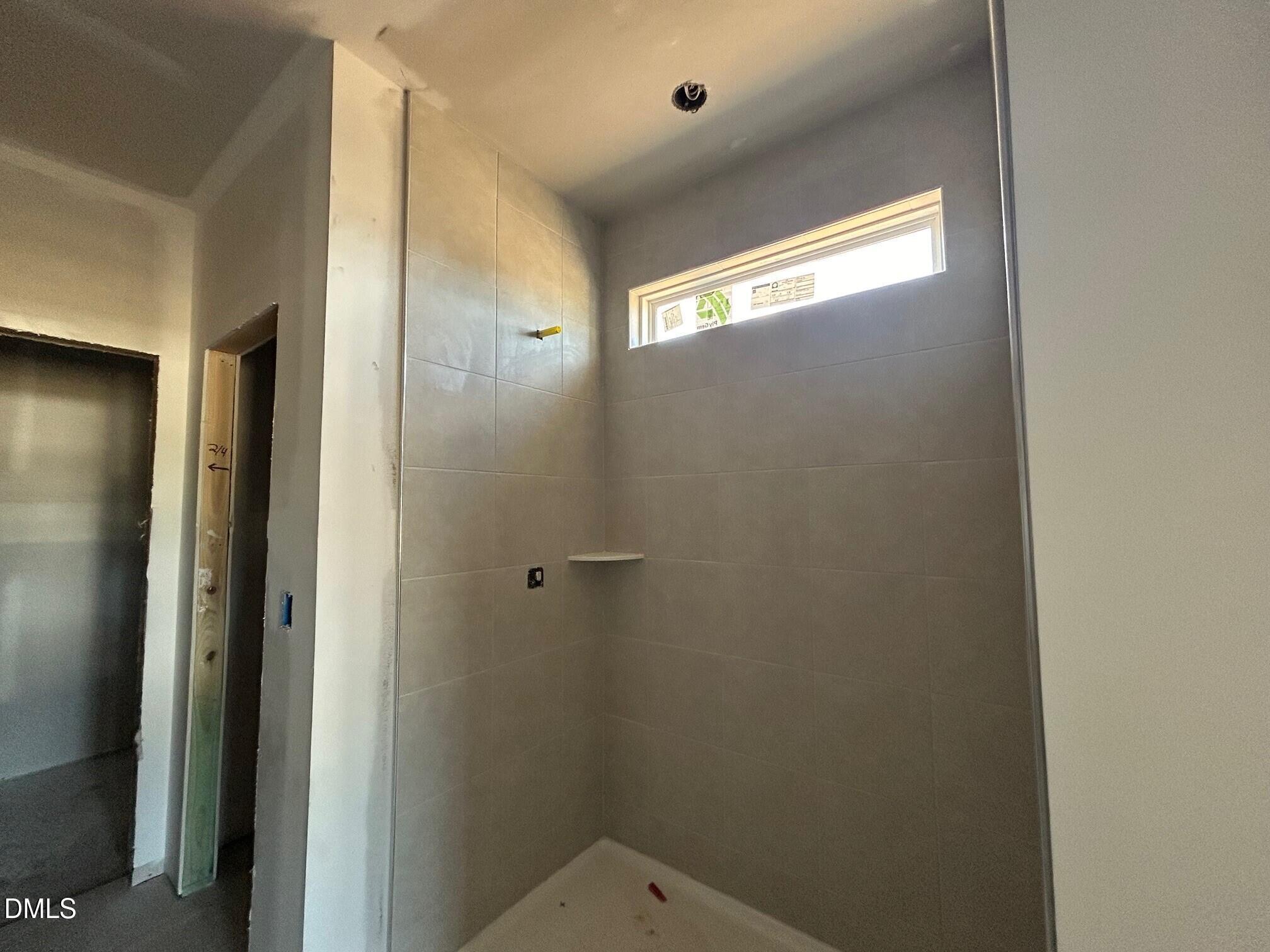 Spacious walk-in shower with gray subway tiles and clerestory window in master bath of Davidson Homes The Daphne D, Lillington, NC