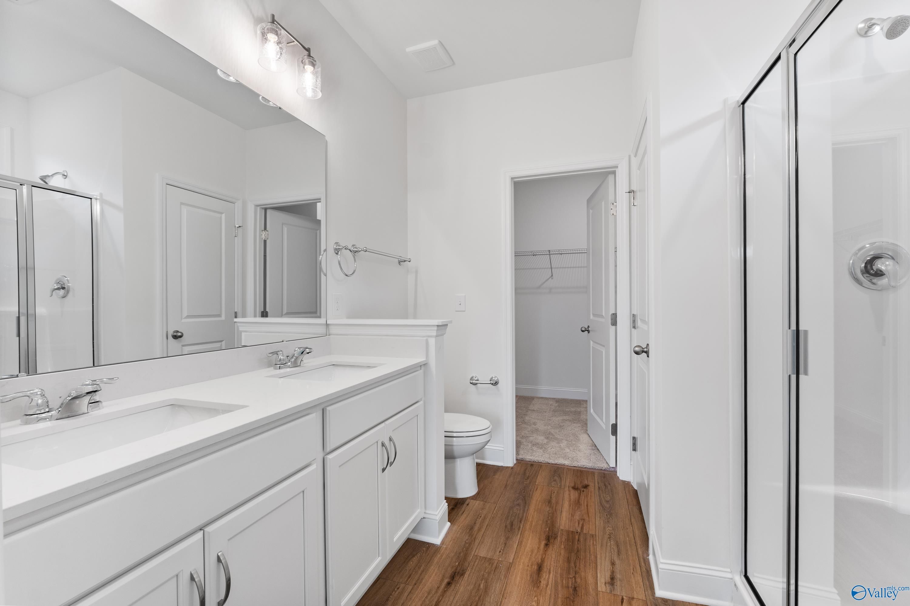Modern master bathroom with double vanity, frameless glass shower, and adjacent walk-in closet in Davidson Homes The Asheville C, New Market, Alabama