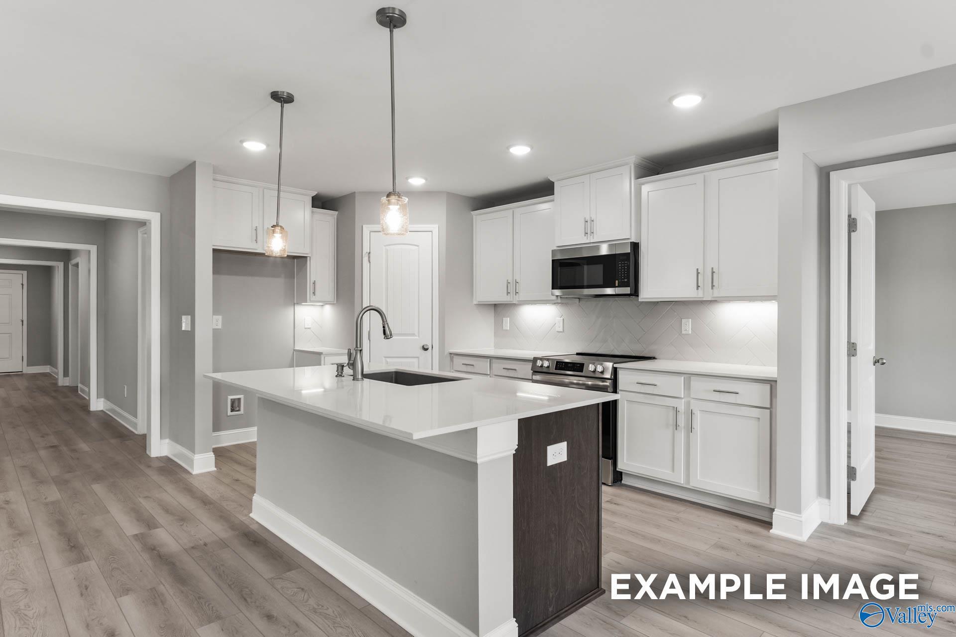 Modern white kitchen with quartz island, stainless appliances, subway backsplash in The Everett B by Davidson Homes, Toney, Alabama