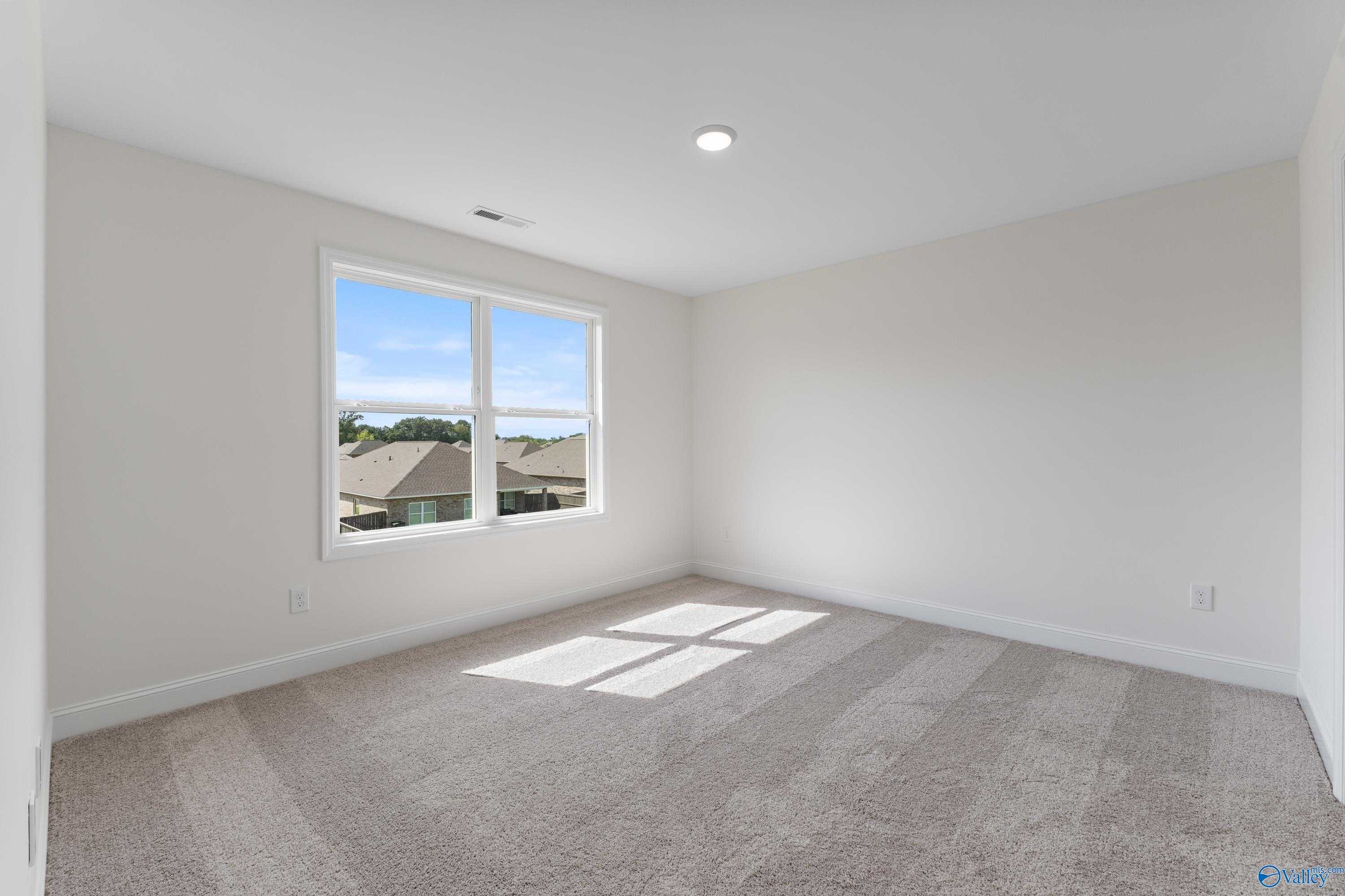 Bright bedroom with beige carpet, large window overlooking neighborhood in Davidson Homes The Shelby A, New Market, Alabama