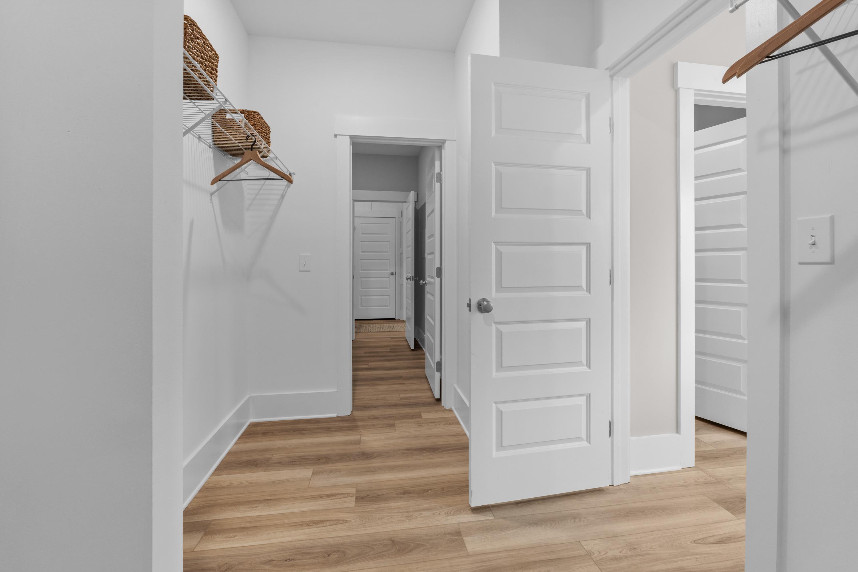 Spacious walk-in closet at The Highlands in Arab Alabama with open white panel doors, wooden hangers, woven baskets, and light oak floors