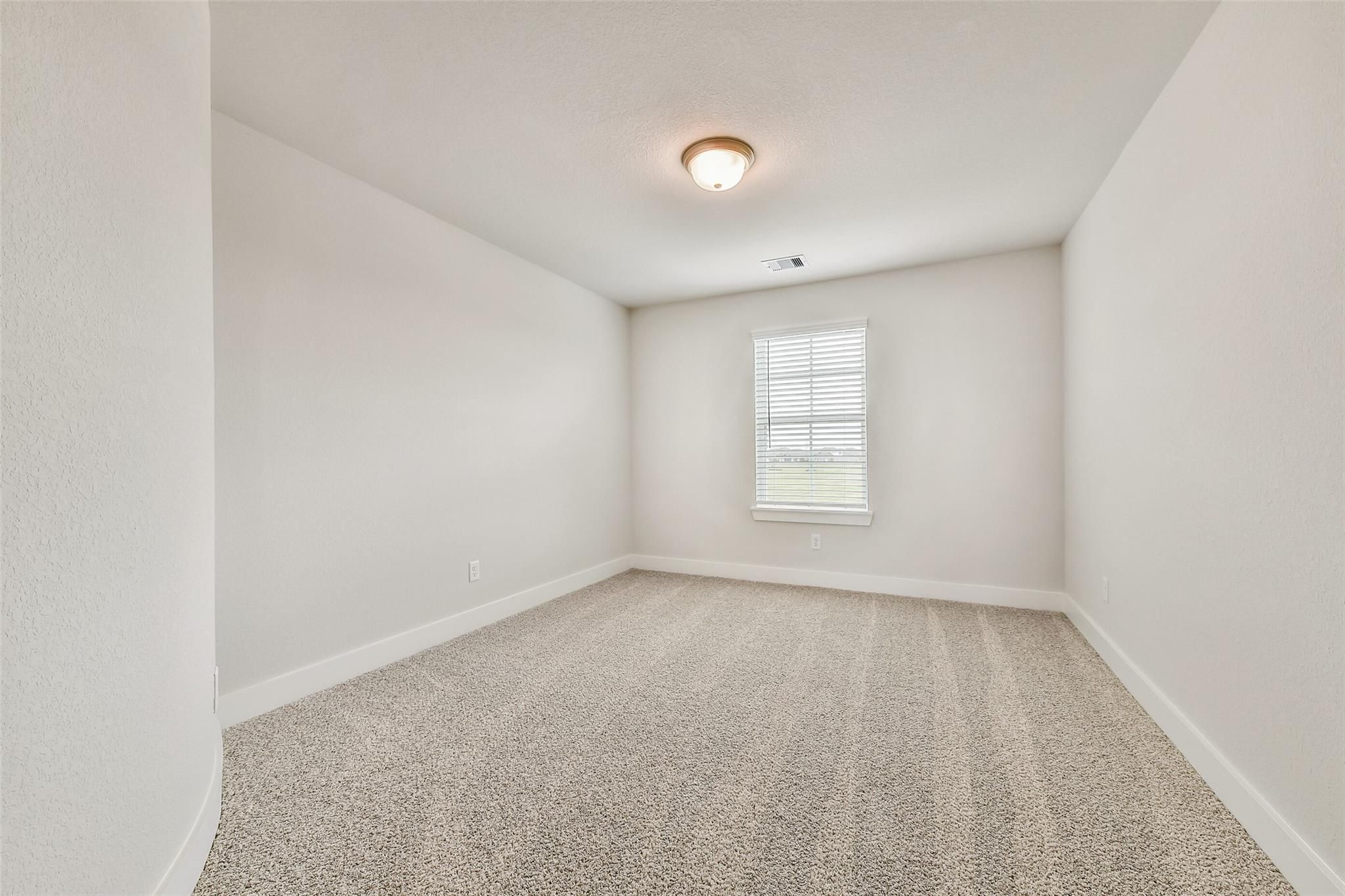 Empty secondary bedroom featuring white walls, neutral carpet, window blinds, and ceiling light in Davidson Homes The Victoria A, Lago Mar, Texas City