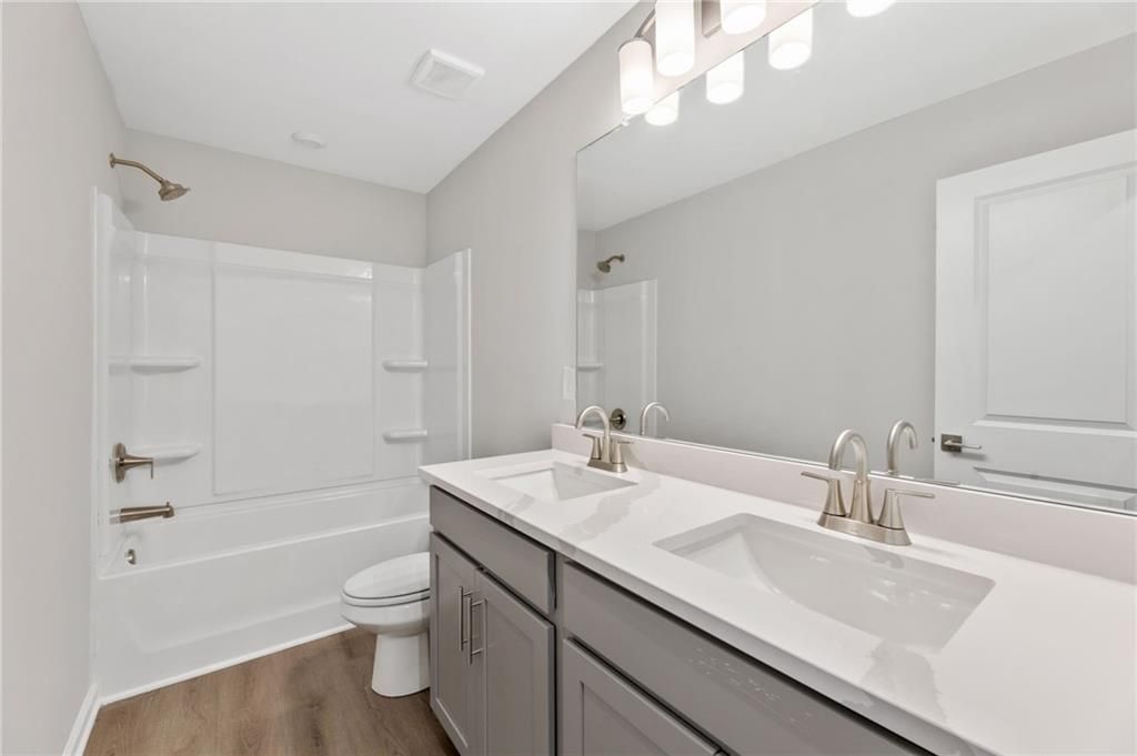 Modern secondary bathroom featuring double vanity, bathtub-shower combo, and gray cabinetry in Davidson Homes The Marion A, Winder, Georgia