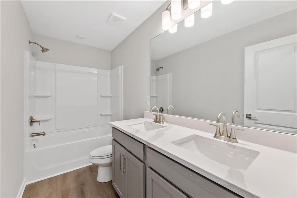 Modern secondary bathroom featuring double vanity, bathtub-shower combo, and gray cabinetry in Davidson Homes The Marion A, Winder, Georgia