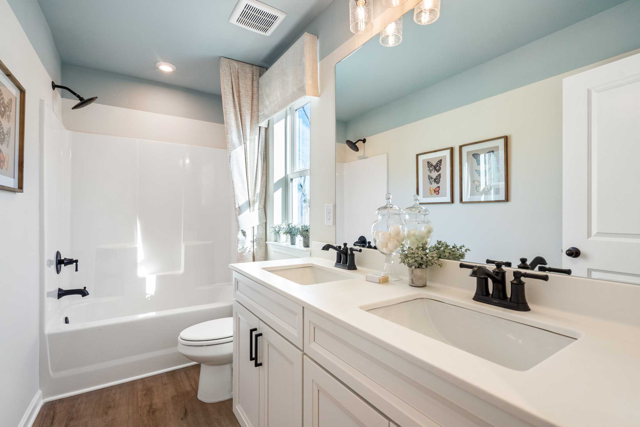 Spacious bathroom at The Village at Shallowford in Kennesaw GA with double vanity, bathtub, shower, blue ceiling, and hardwood floors by Davidson Homes